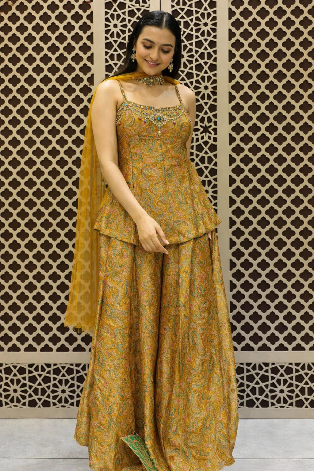 Woman wearing a mustard yellow traditional outfit with a patterned background