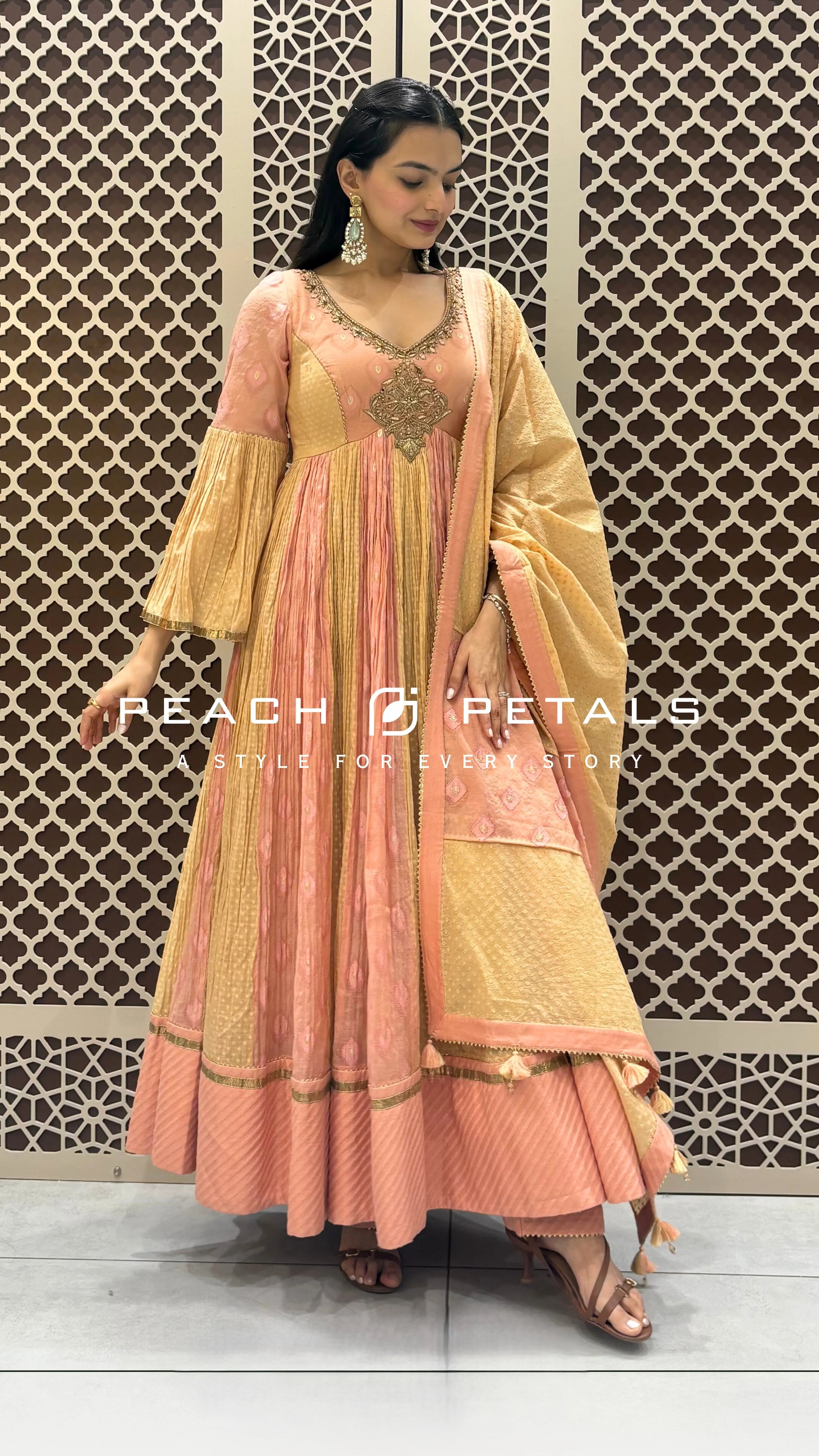 Peach and gold silk Anarkali featuring intricate neckline embroidery, pleated panels, and a matching tasseled dupatta.