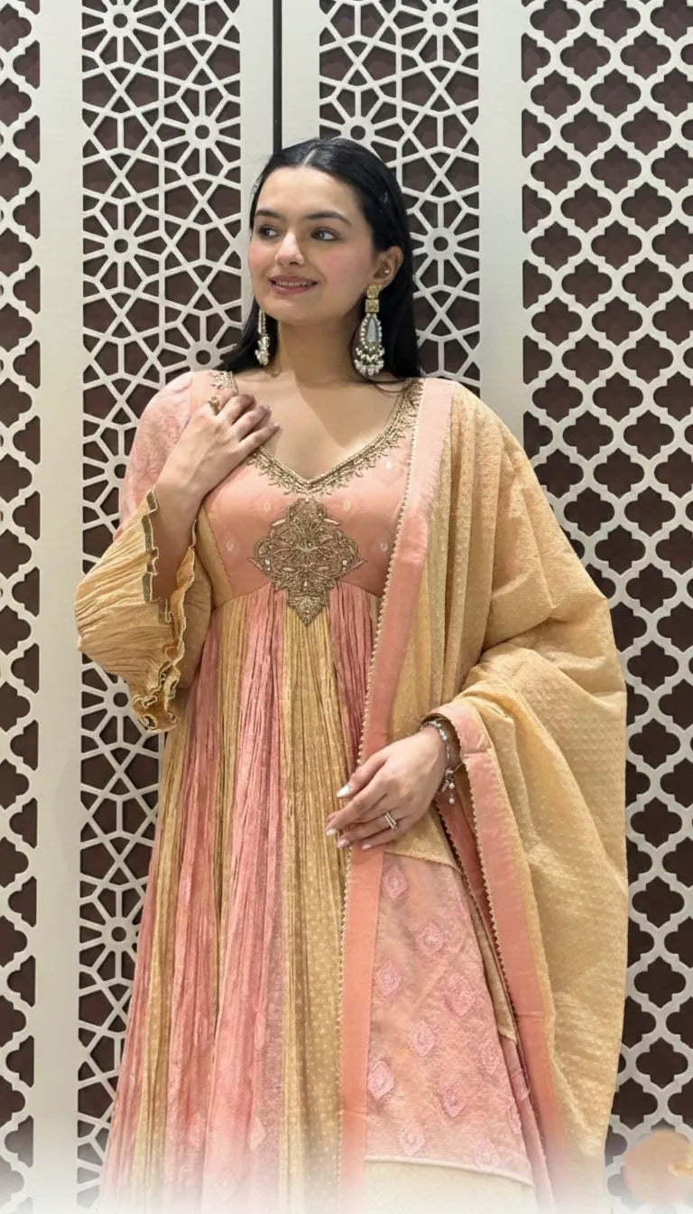 Peach and gold silk Anarkali featuring intricate neckline embroidery, pleated flare, and a tasselled dupatta.