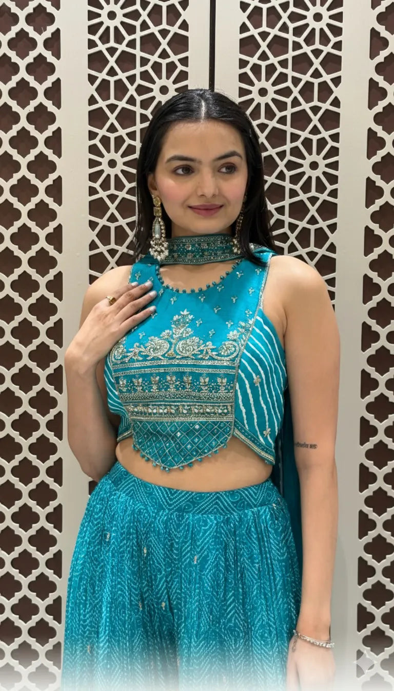 Teal Bandhani print crop top with silver embroidery paired with matching flared sharara and dupatta.