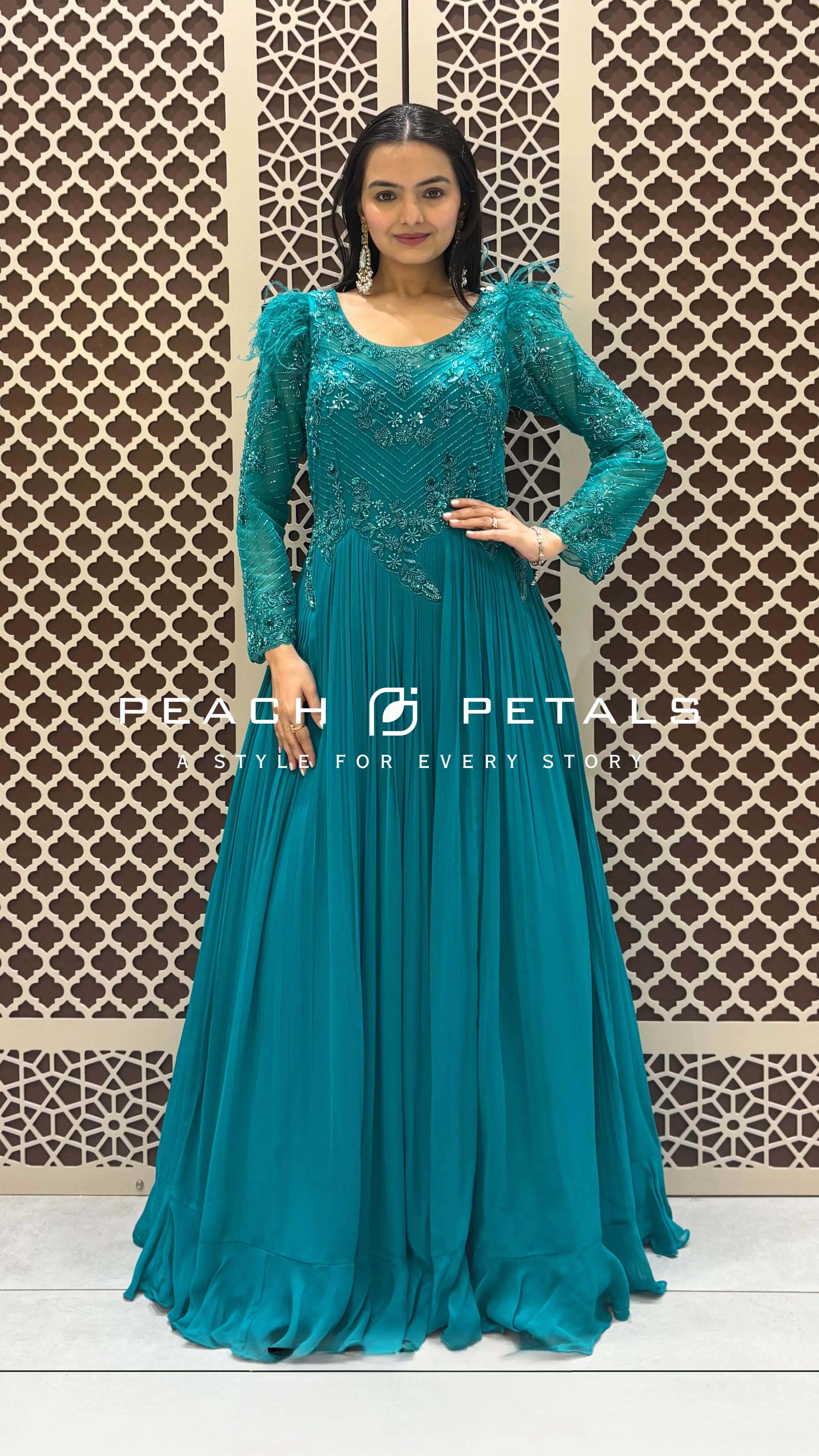Elegant teal floor-length gown featuring intricate bodice embroidery and dramatic feather-trimmed long sleeves for evening wear.
