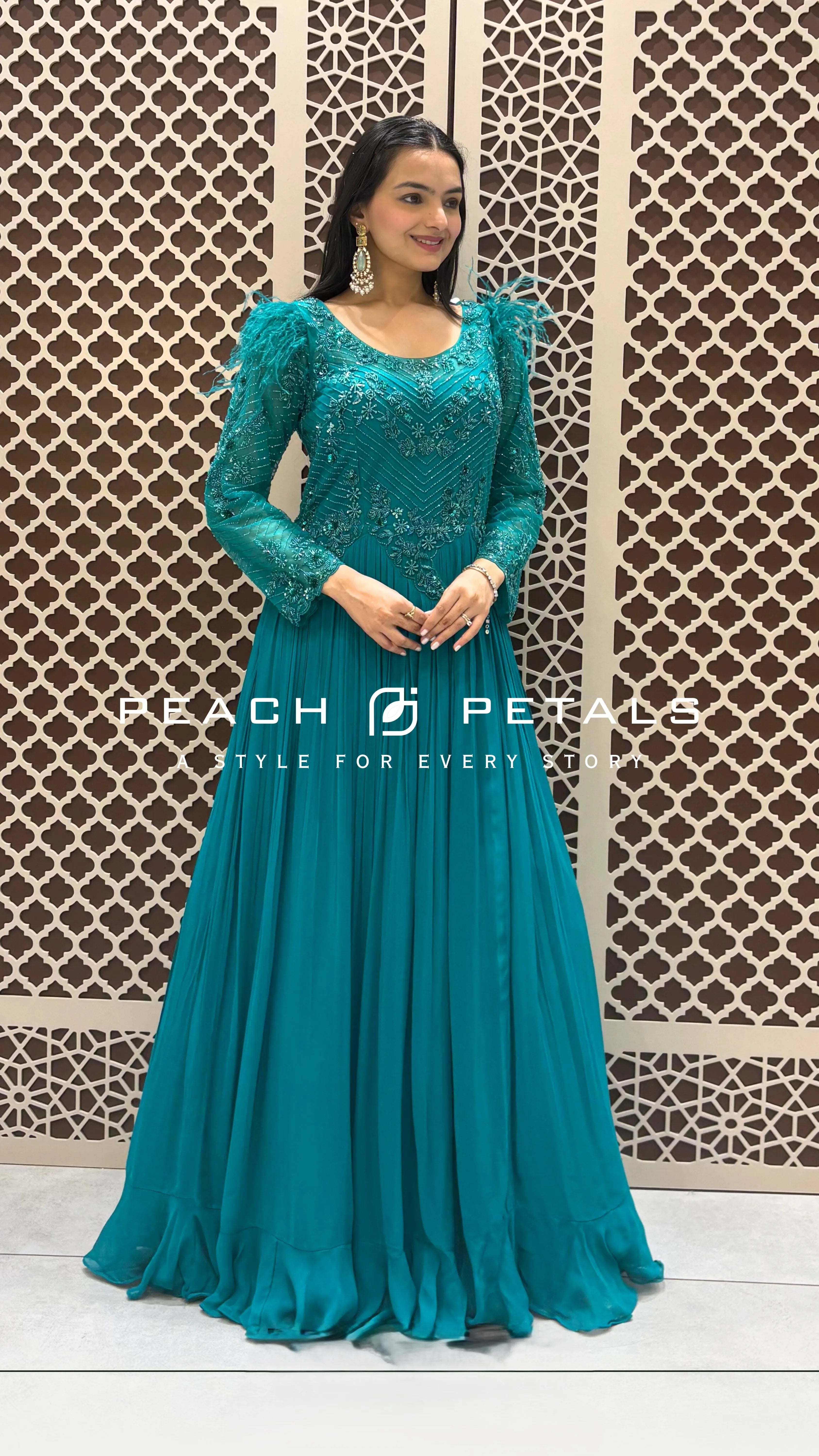 Stunning teal floor-length gown featuring intricate embroidery and unique feather-trimmed sleeves for a festive look.
