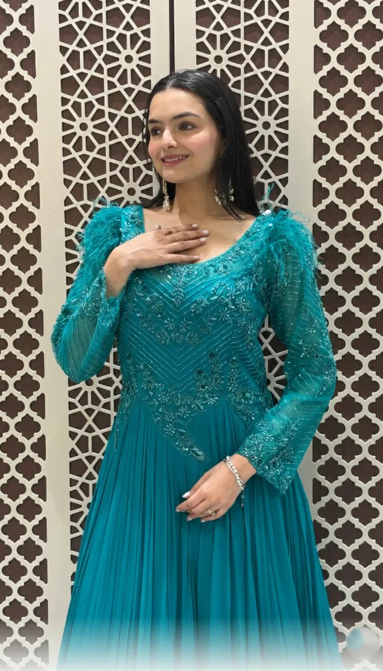 Elegant teal floor-length gown featuring intricate bodice embroidery and dramatic feather-trimmed long sleeves for formal events.