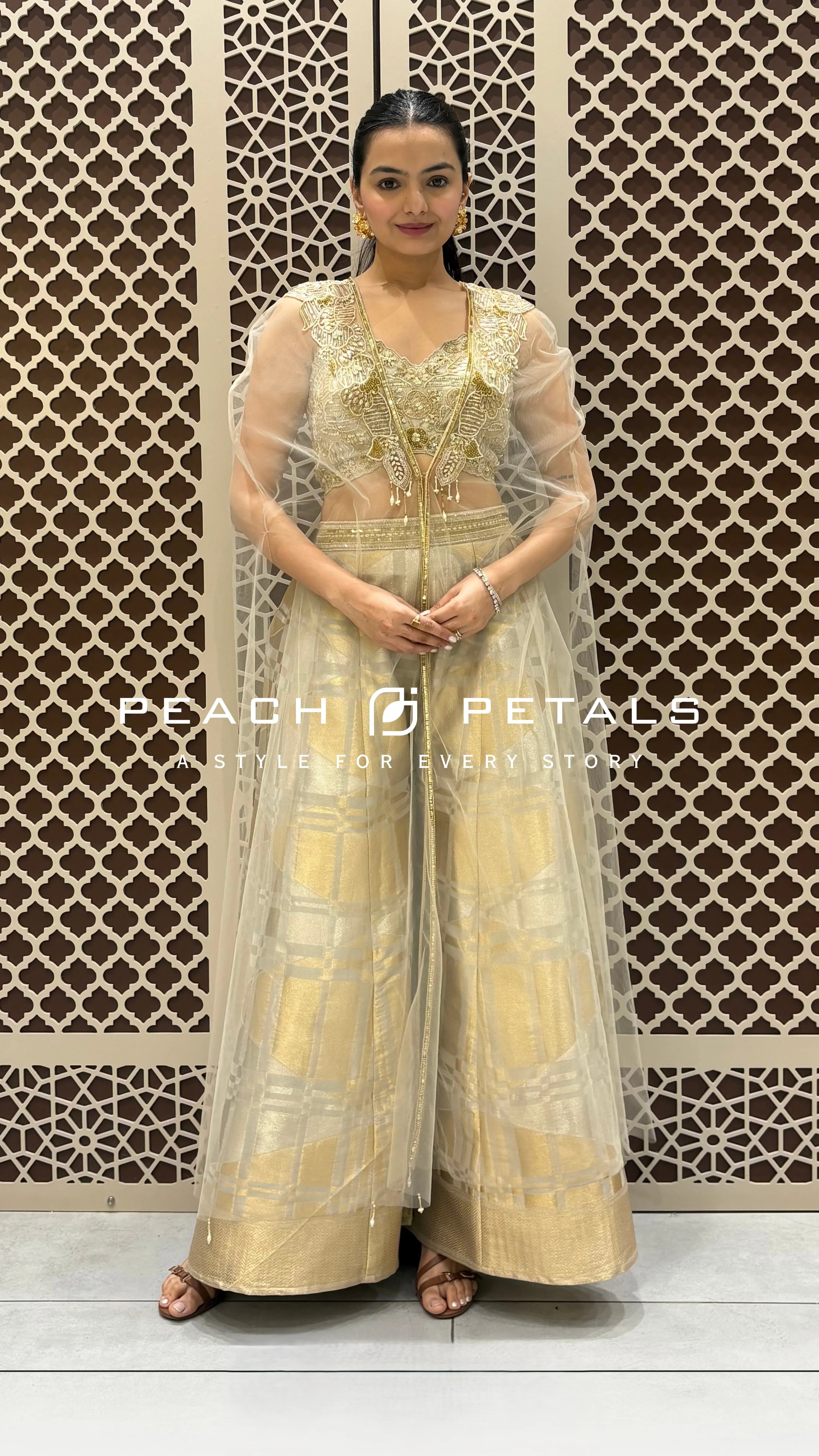 Gold Indo-Western set featuring a sequined sleeveless top, patterned wide-leg trousers, and a sheer embroidered cape.