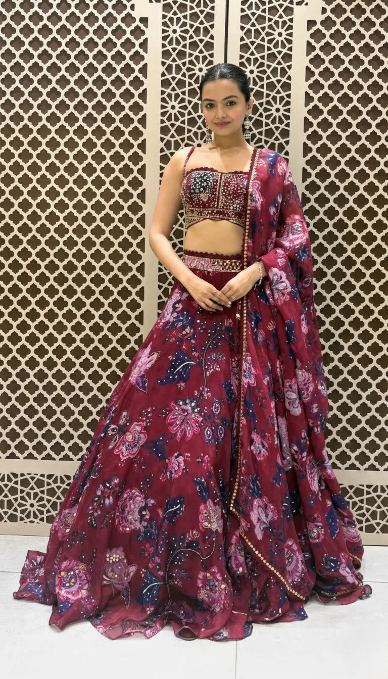 Maroon lehenga featuring vibrant floral prints paired with a matching heavily embroidered strappy crop top.