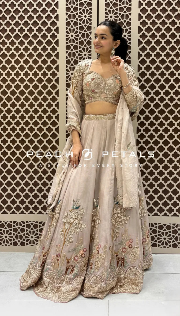 Light peach lehenga featuring intricate floral and animal embroidery with a matching scalloped border dupatta.