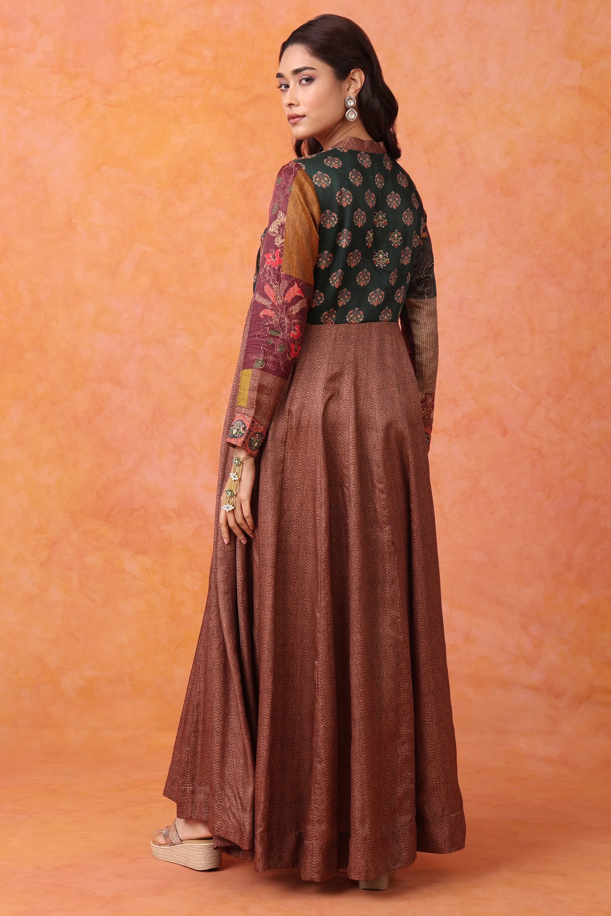 Woman wearing a traditional outfit with a green top and brown skirt on an orange background