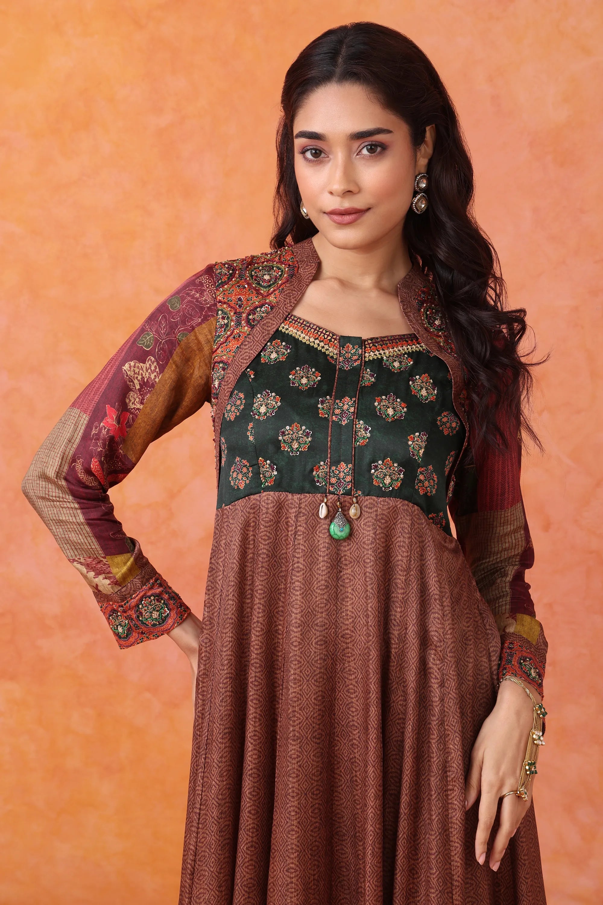 Woman wearing a traditional outfit with a green top and brown skirt against an orange background