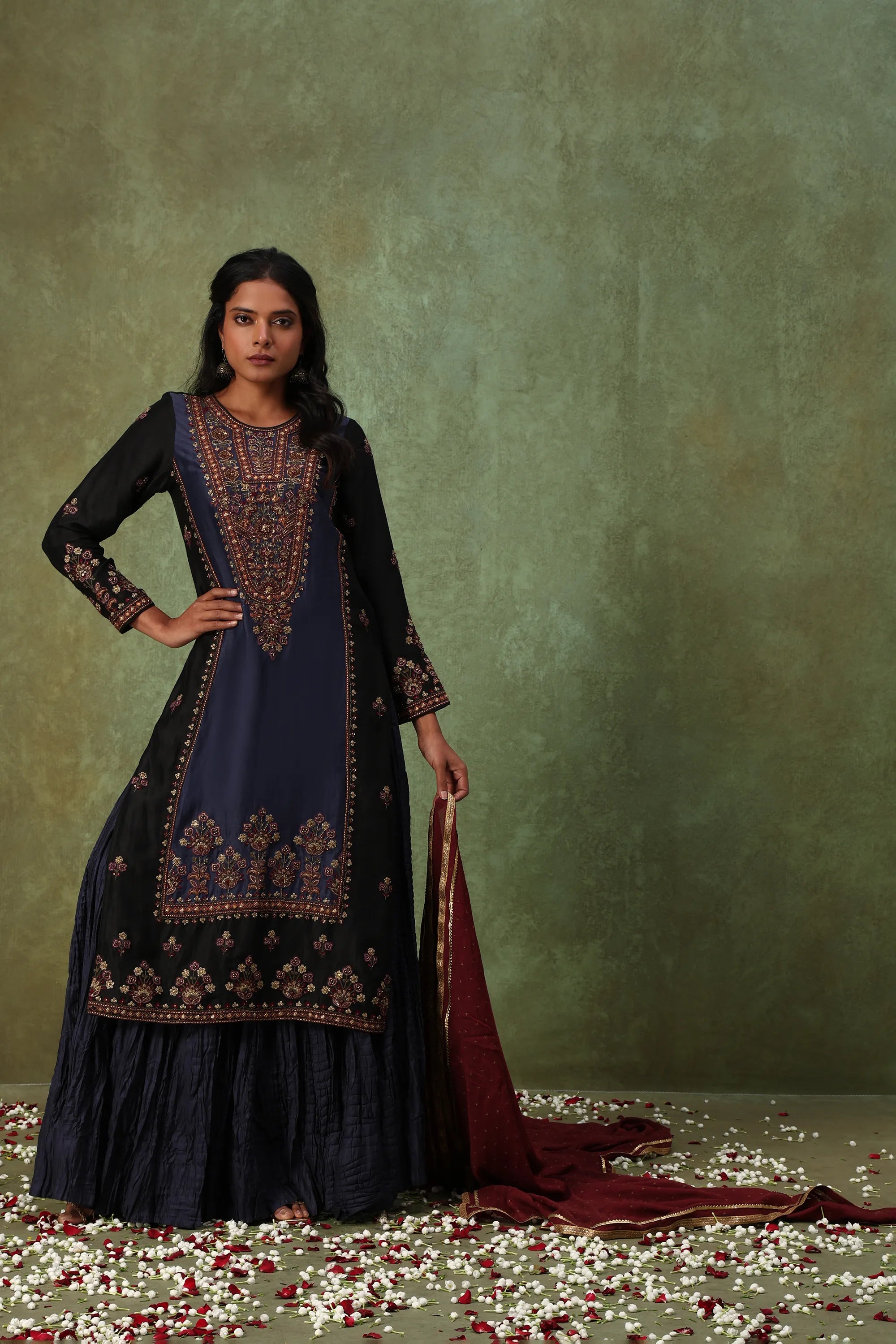 Woman in a traditional embroidered outfit with a green background