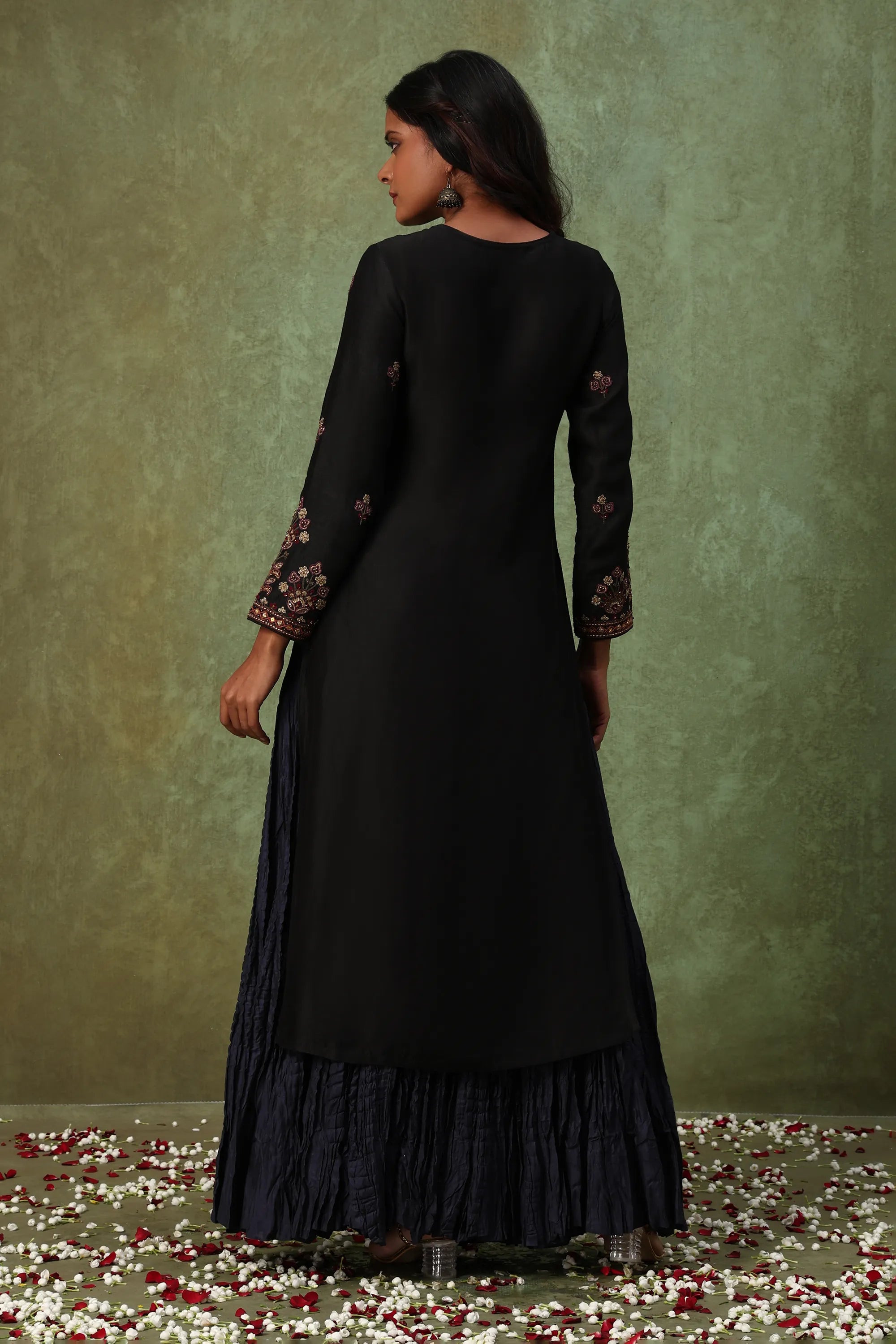 Woman wearing a black dress with floral embroidery on a green background