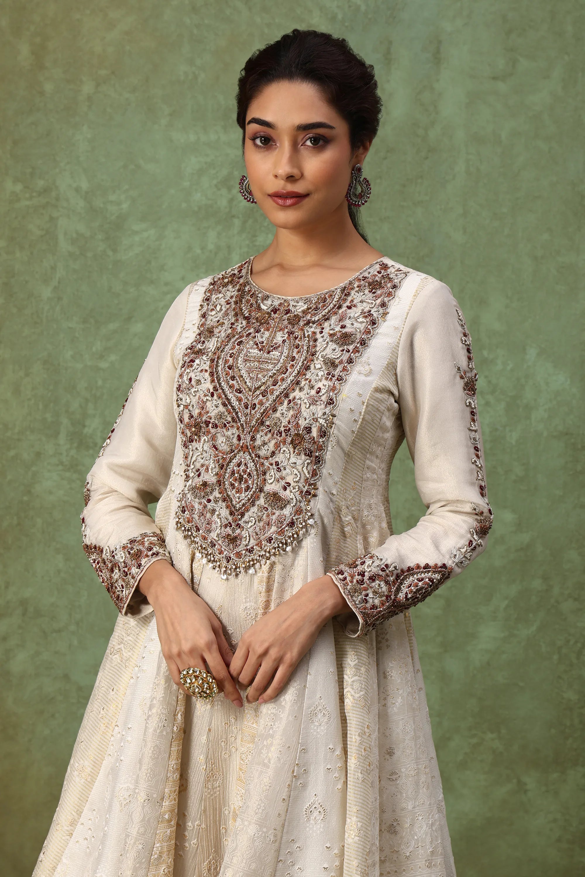 Woman wearing a traditional embroidered outfit against a green background