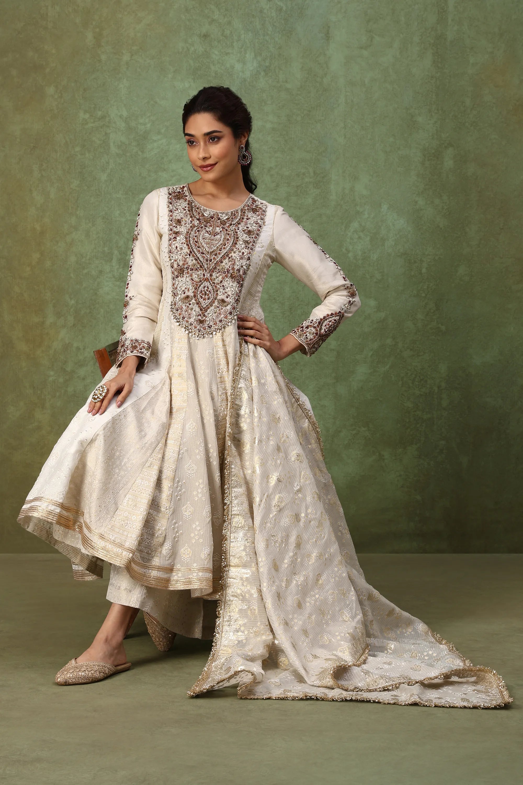 Woman wearing a traditional embroidered outfit against a green background