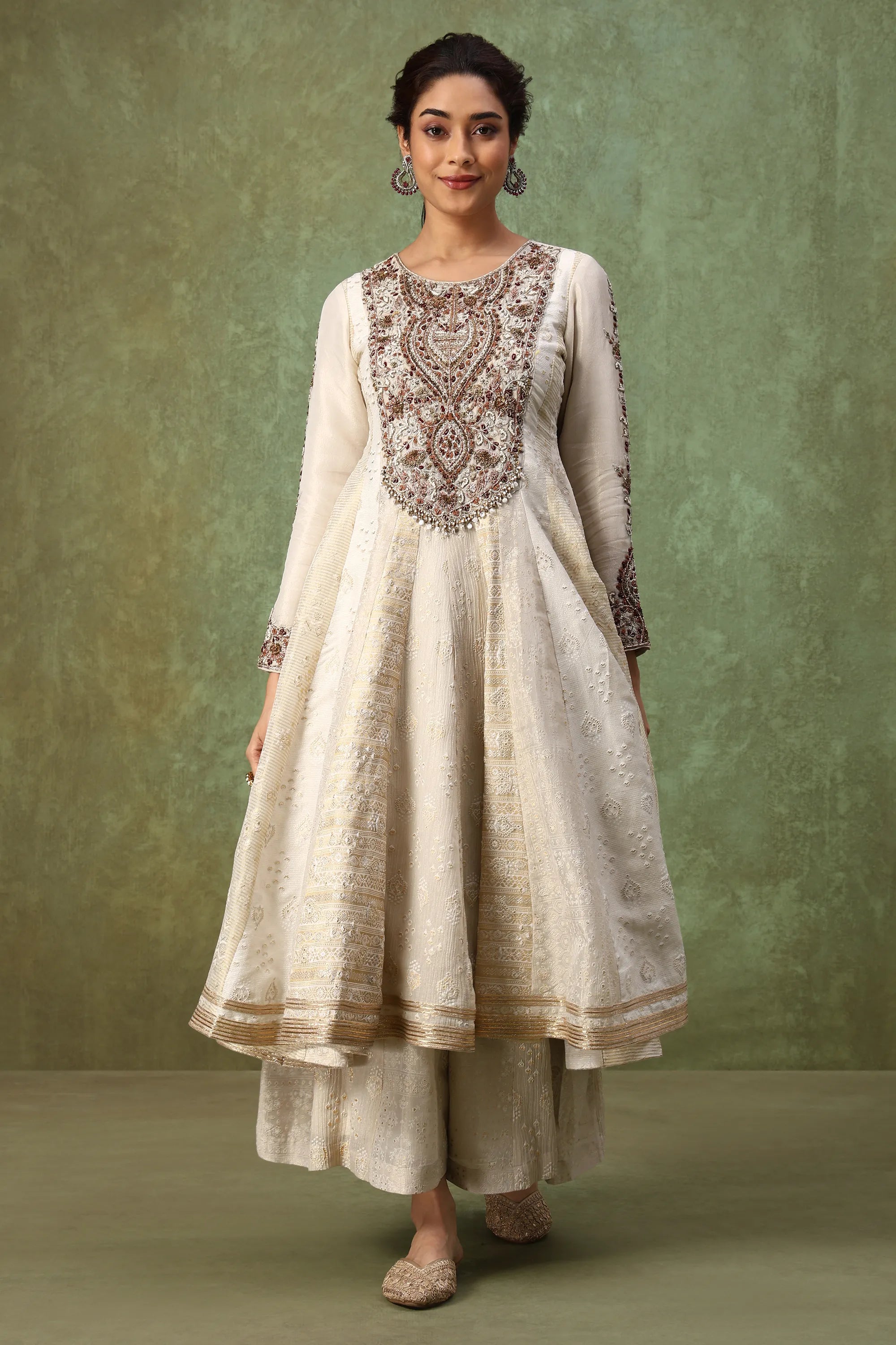 Woman wearing a traditional outfit with intricate embroidery against a green background