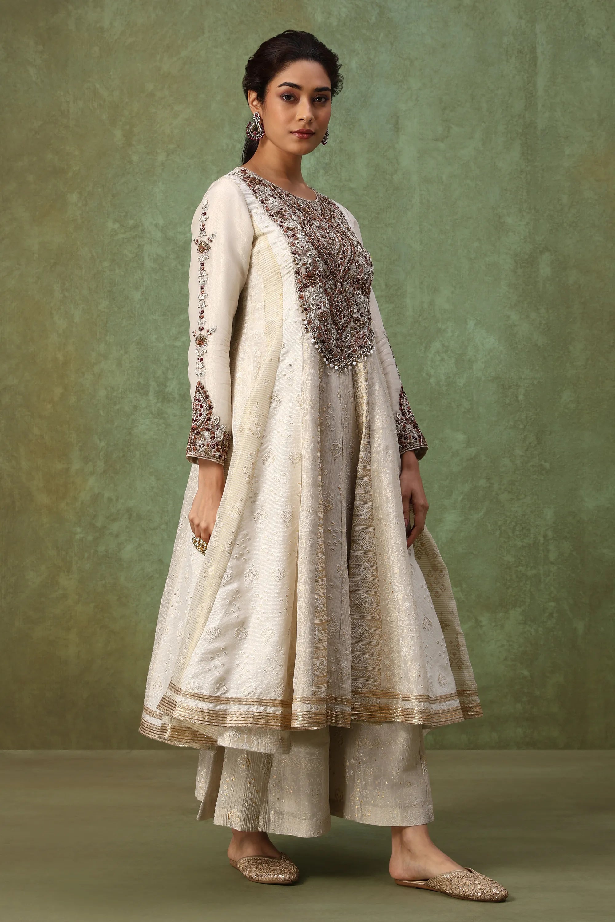 Woman wearing a traditional outfit with intricate embroidery against a green background