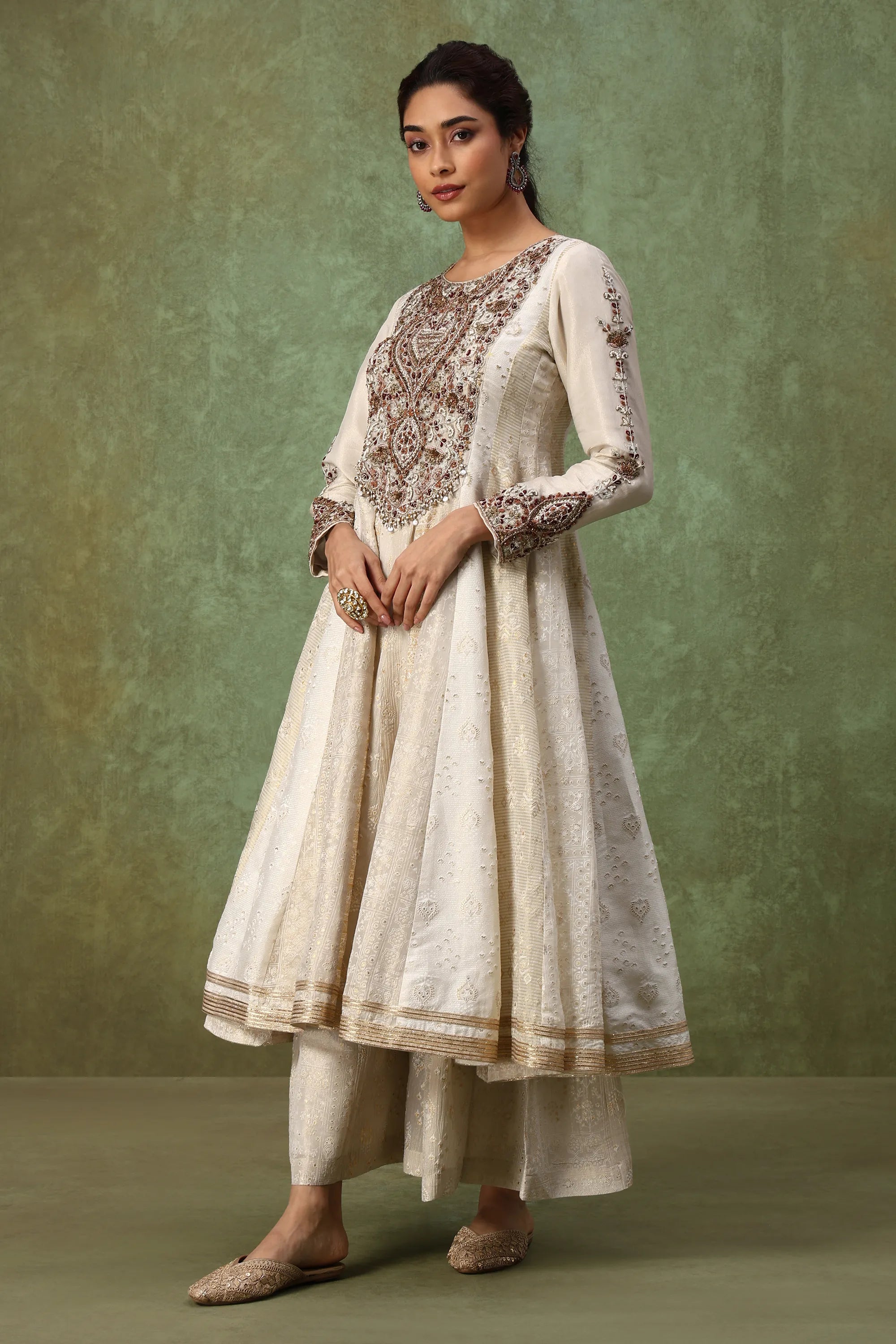 Woman wearing a traditional outfit with intricate embroidery against a green background