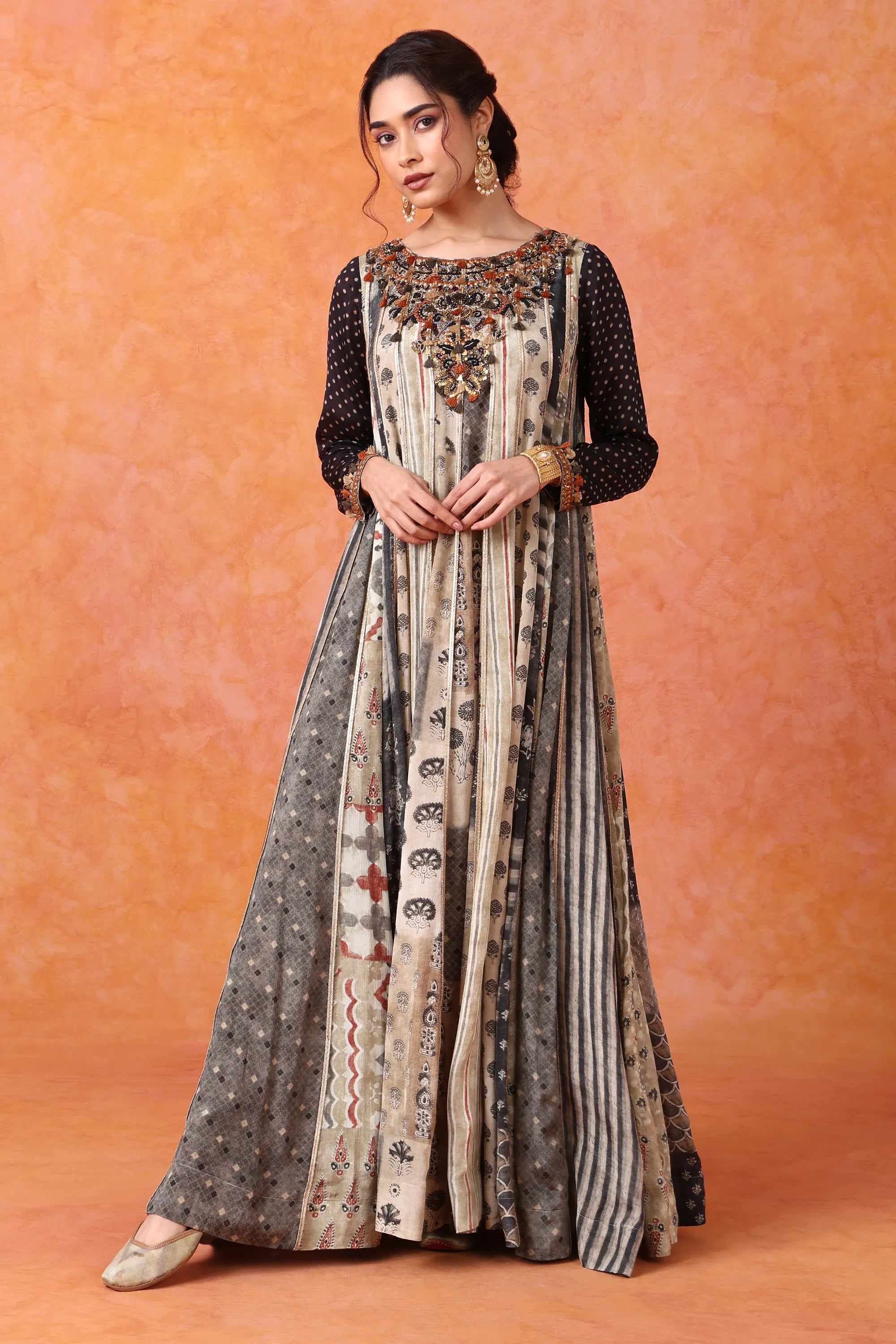 Woman wearing a long, patterned dress against an orange background