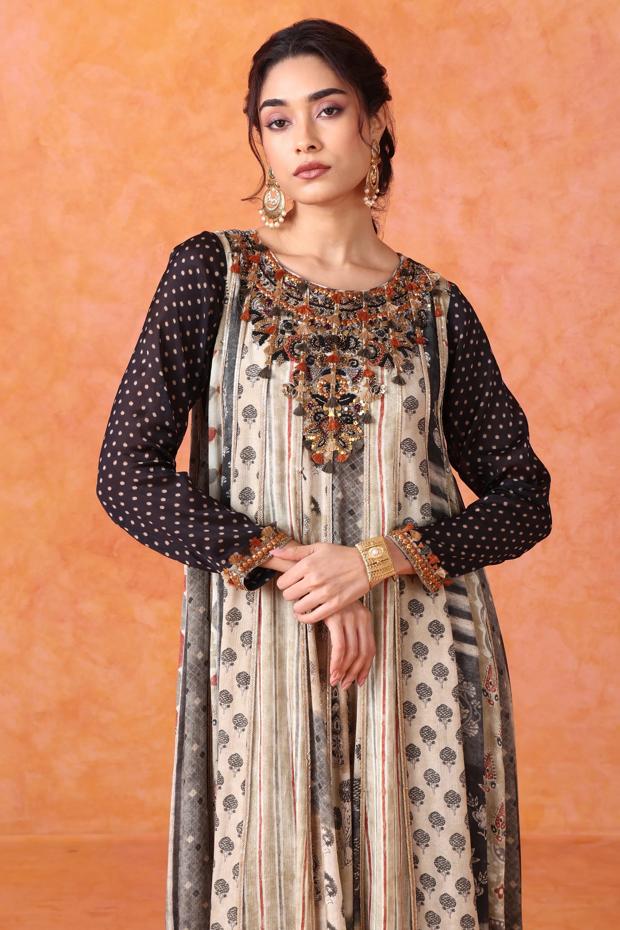 Woman wearing a traditional outfit with intricate designs against an orange background