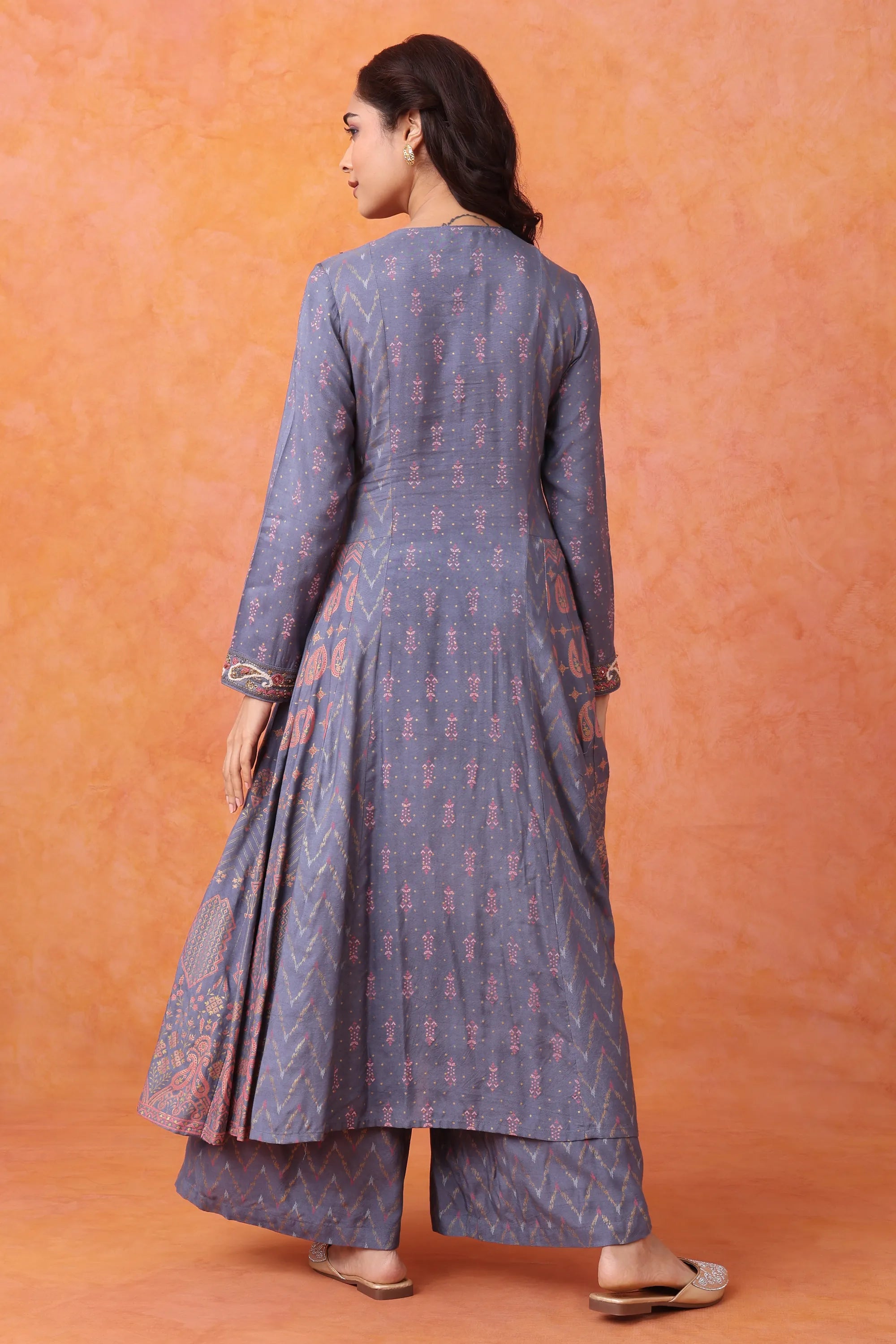 Woman wearing a long, patterned dress against an orange background