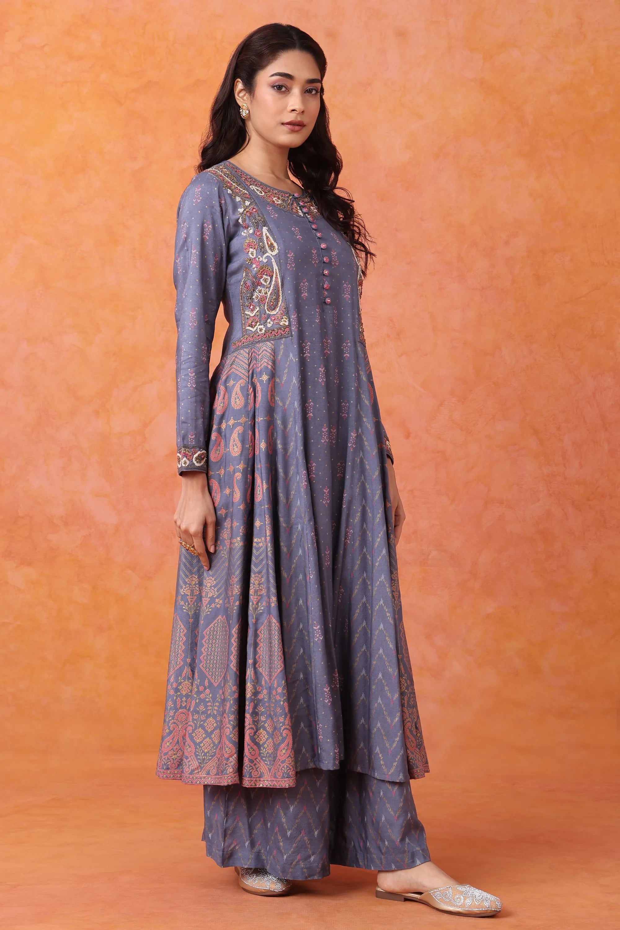 Woman wearing a long, patterned dress against an orange background