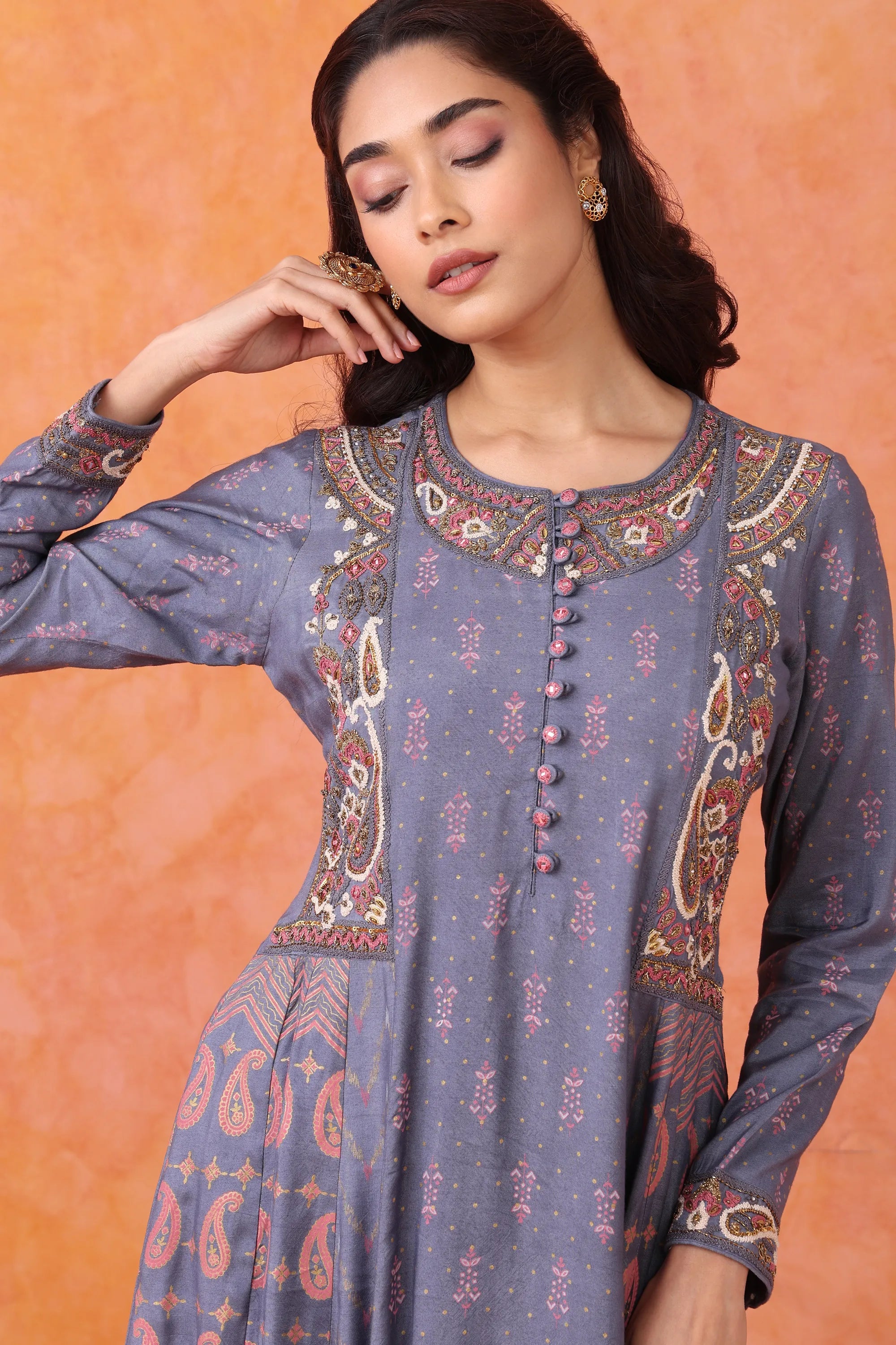 Woman wearing a blue embroidered kurta against an orange background