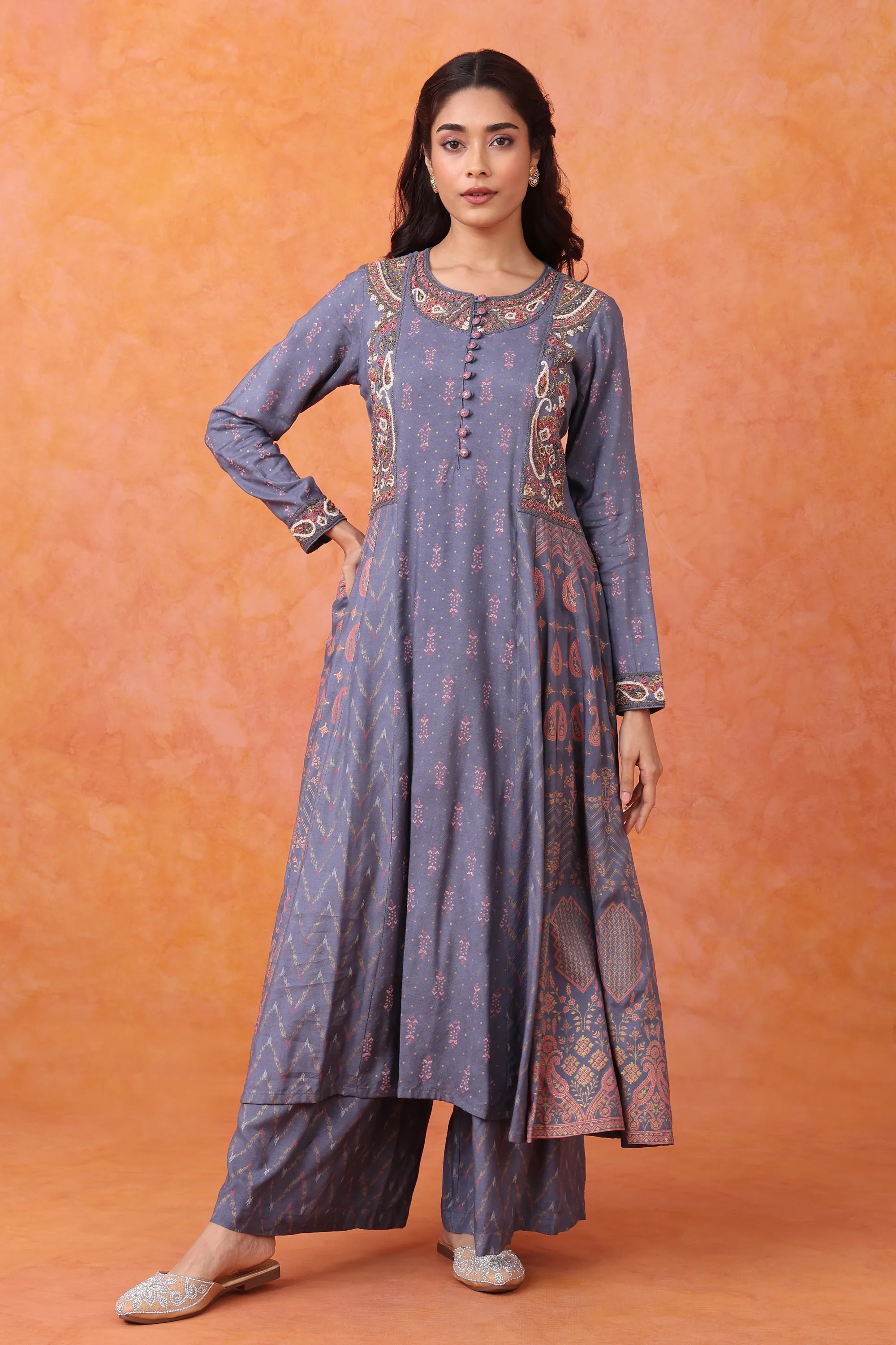 Woman wearing a long, patterned dress against an orange background