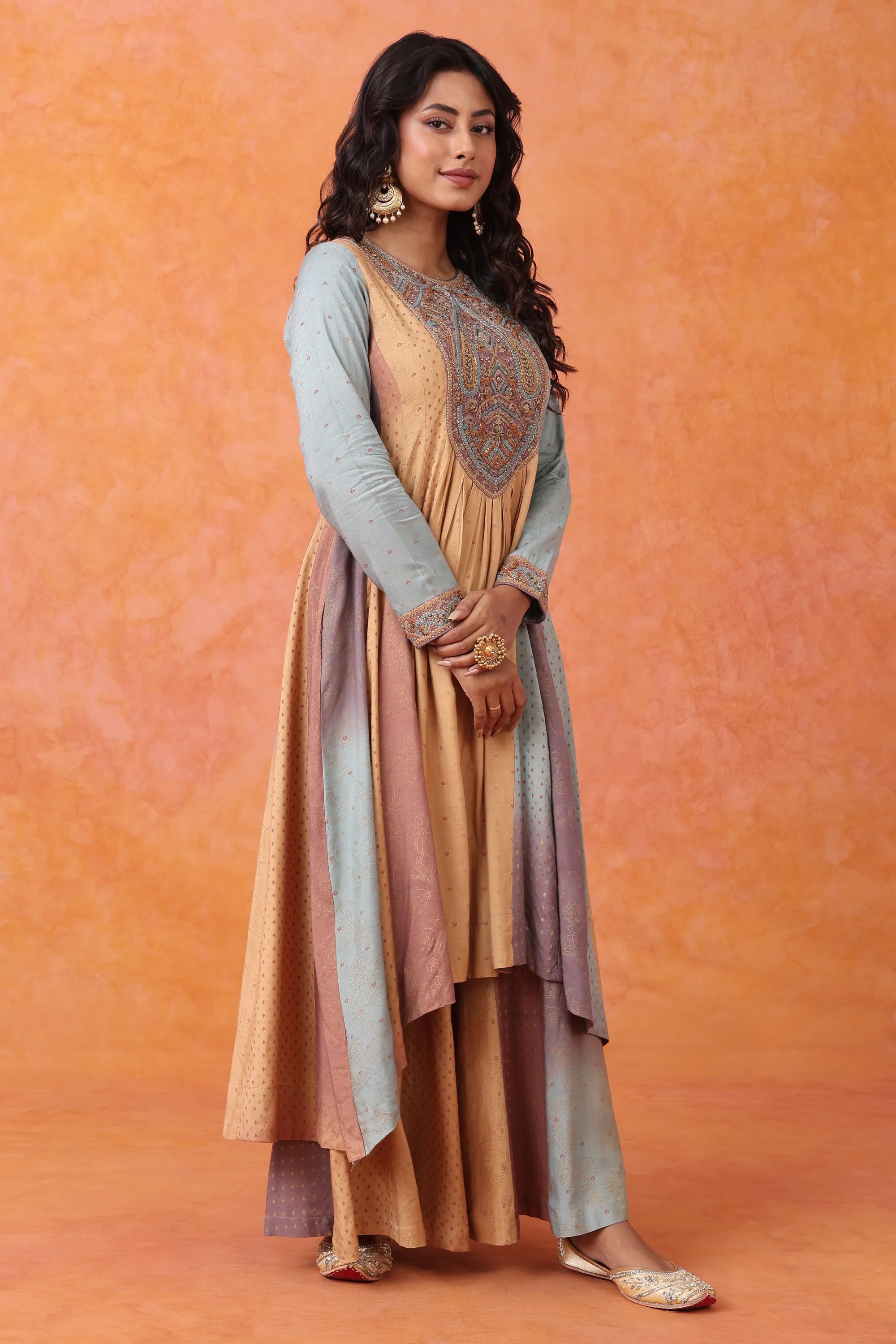 Woman wearing a long, multi-colored dress with an orange background