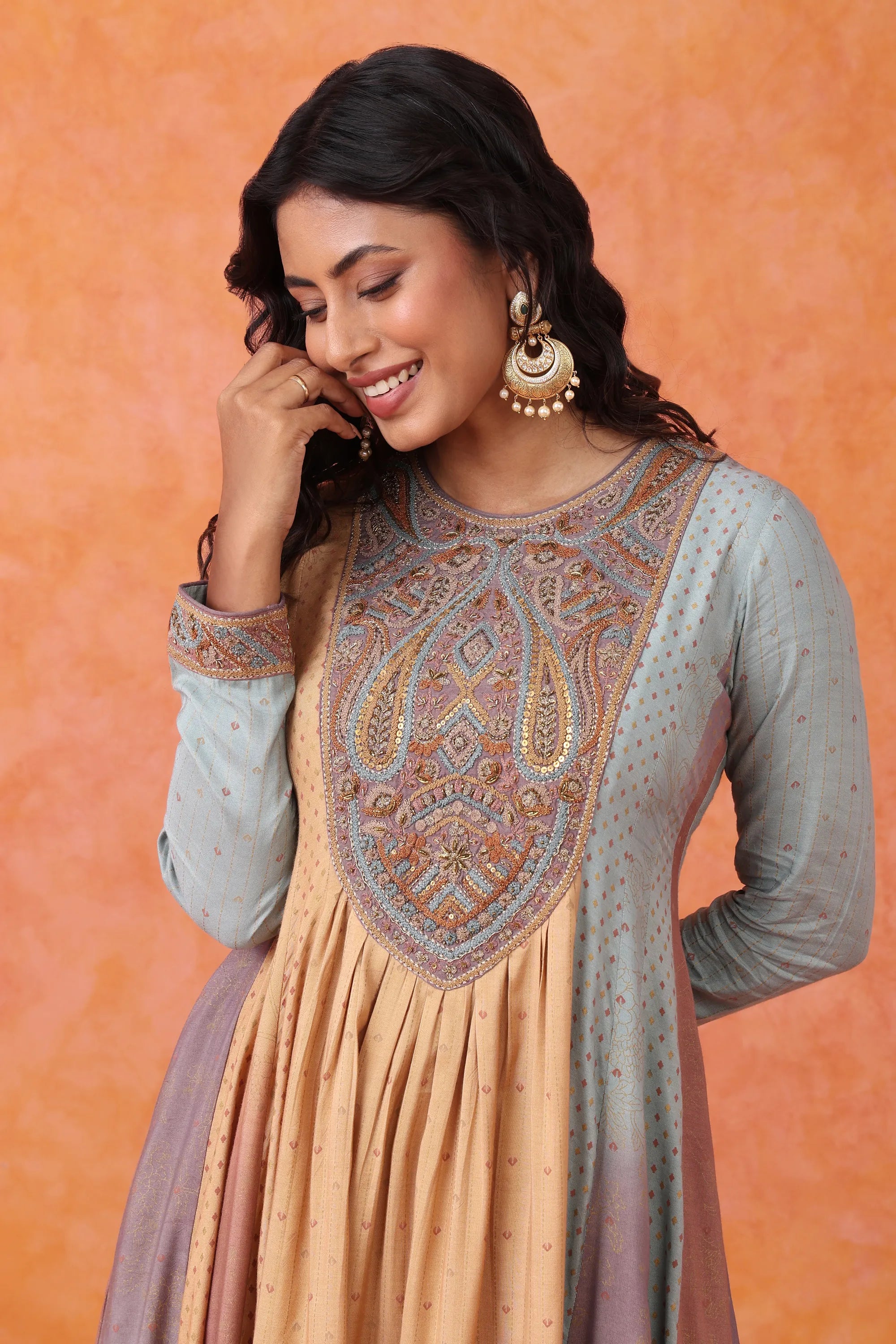 Woman wearing a traditional outfit with intricate patterns on an orange background