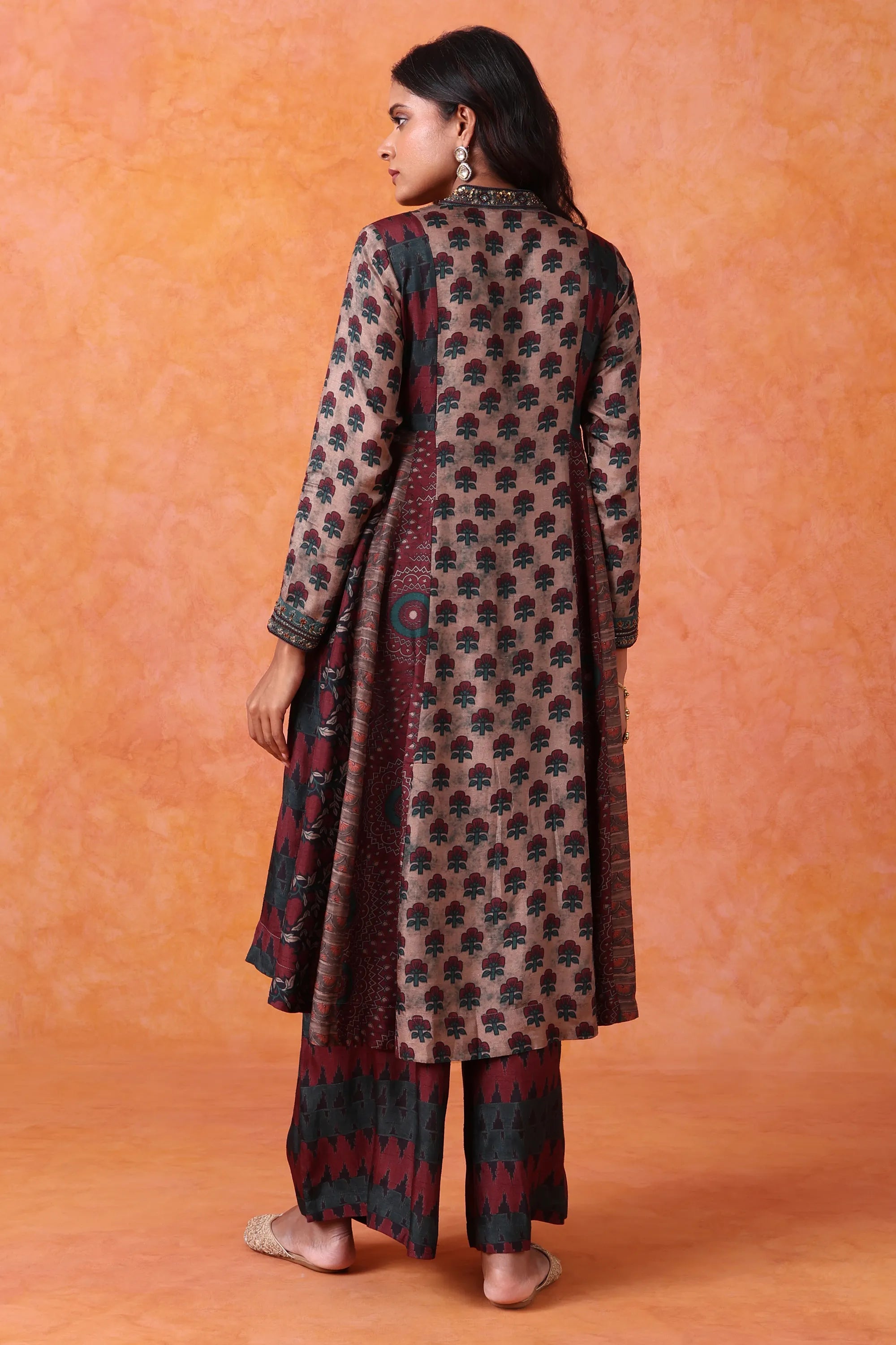 Woman wearing a patterned kurta with maroon and black details on an orange background