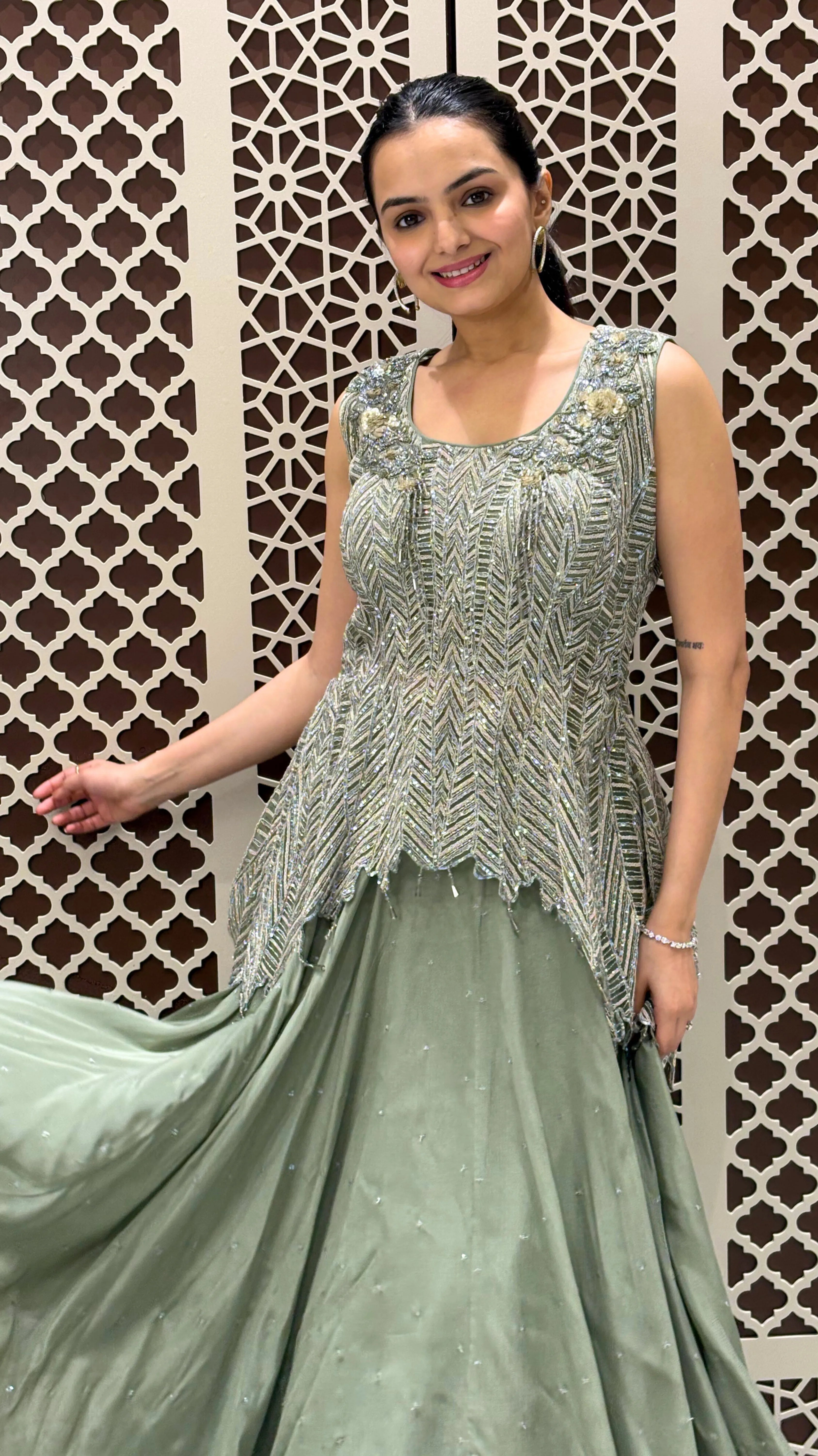 Woman wearing a green traditional outfit with a patterned background