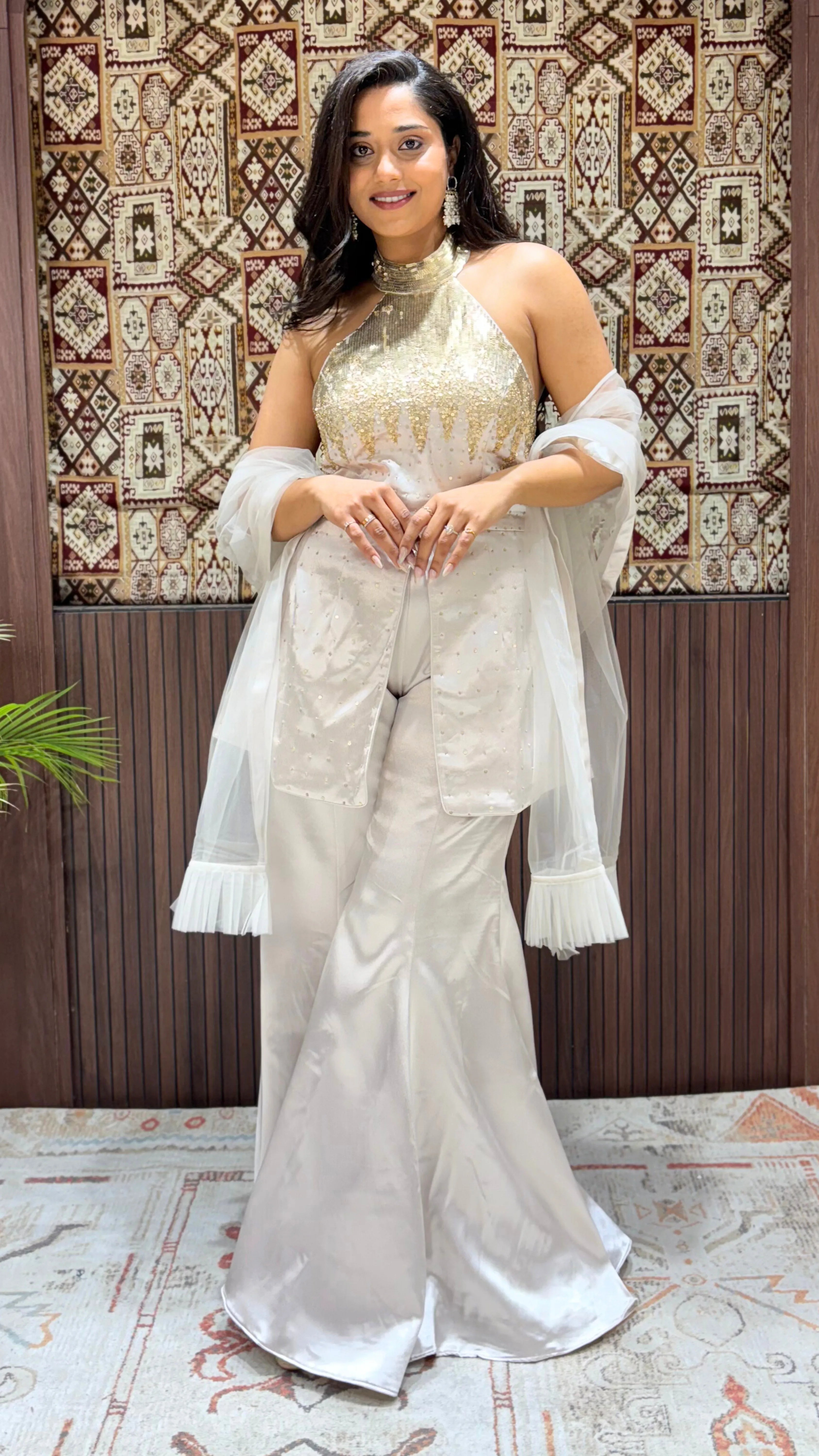 Woman in a white traditional outfit with a patterned wall in the background