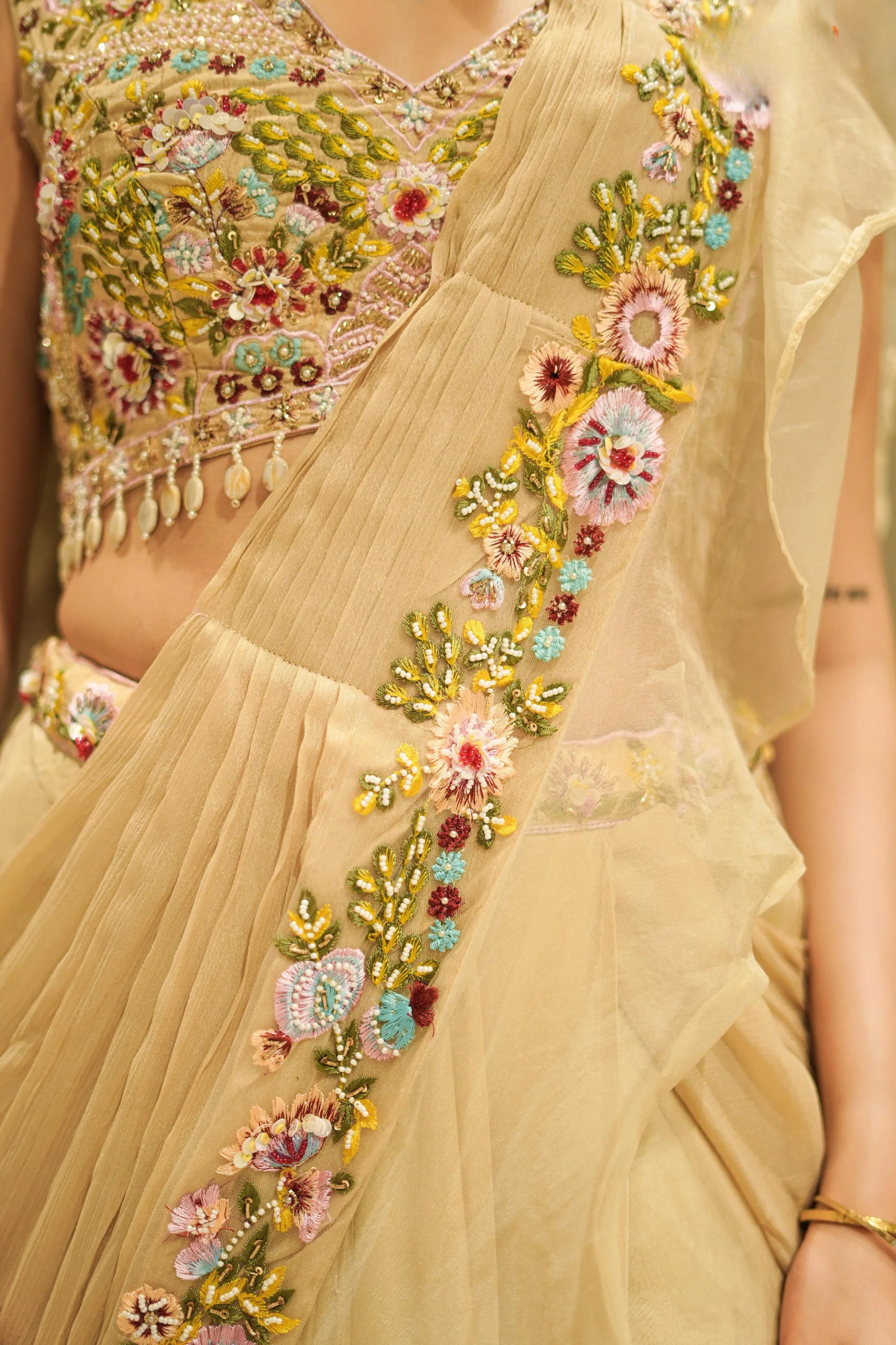 Beige saree with floral embroidery and a matching blouse.