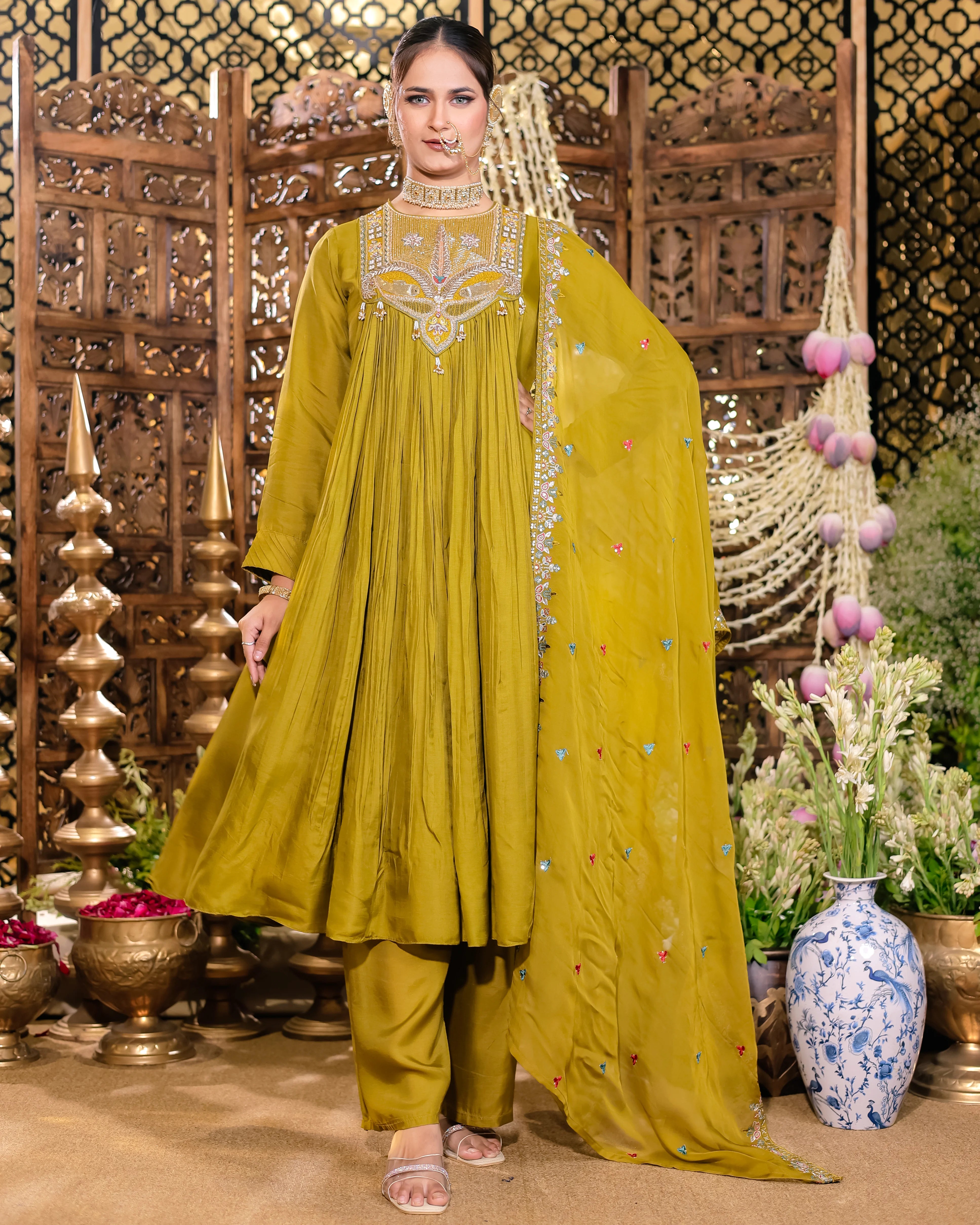 Woman in a traditional yellow outfit with intricate embroidery in a decorated setting.