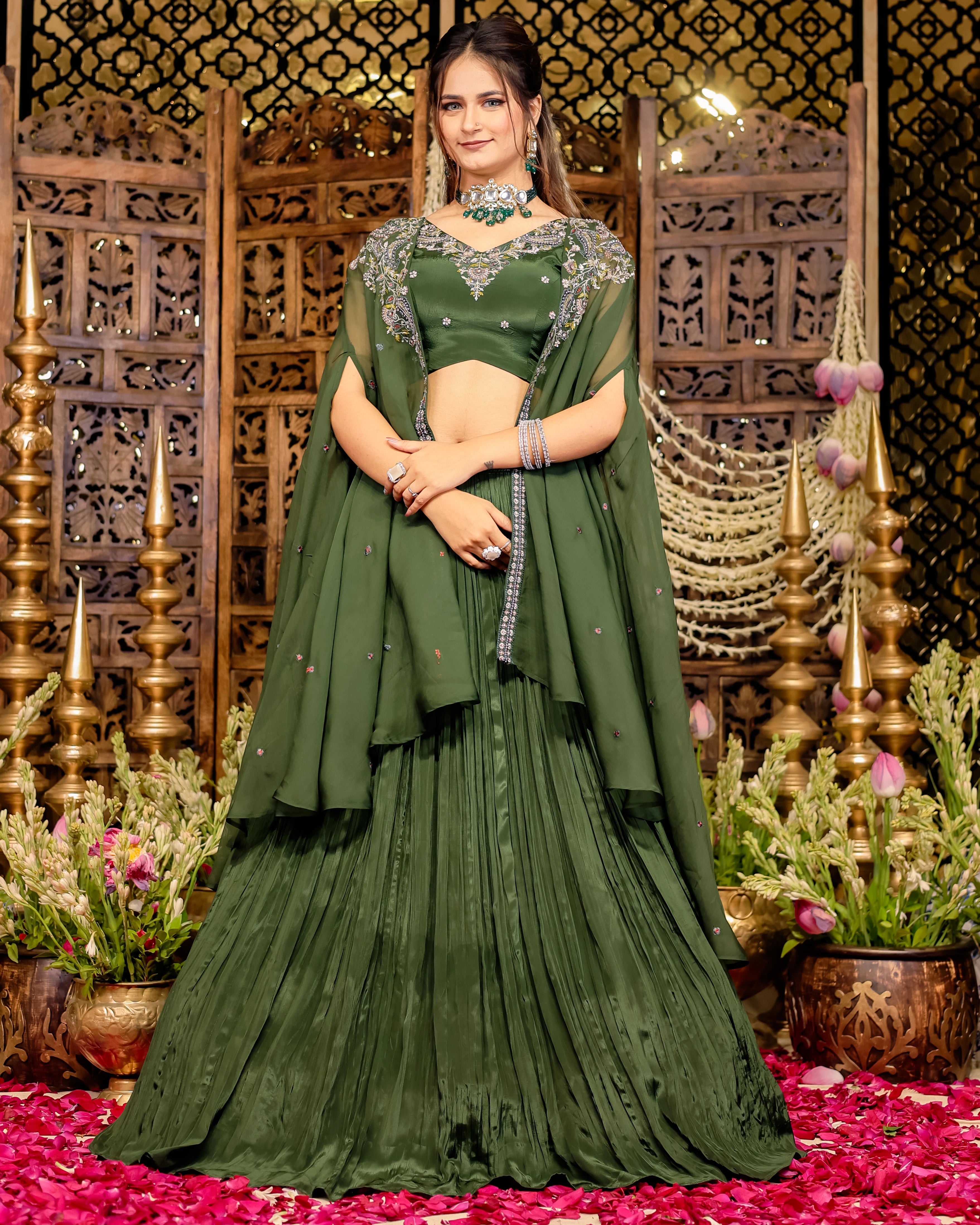 Woman in an olive green pleated lehenga with an embroidered blouse and matching sheer cape.