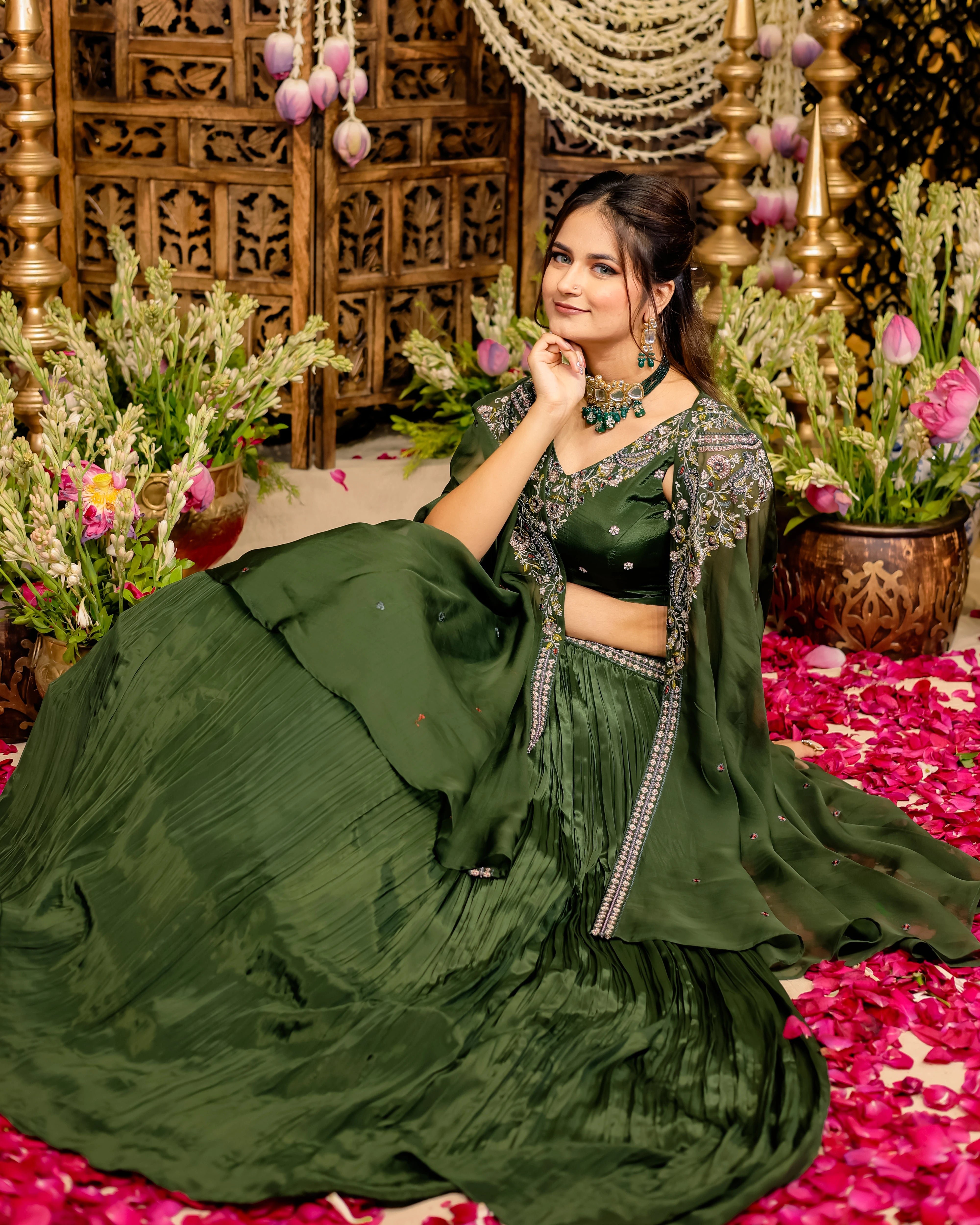 Model wearing an olive green lehenga with intricate resham embroidery, a choli, and a sheer cape.