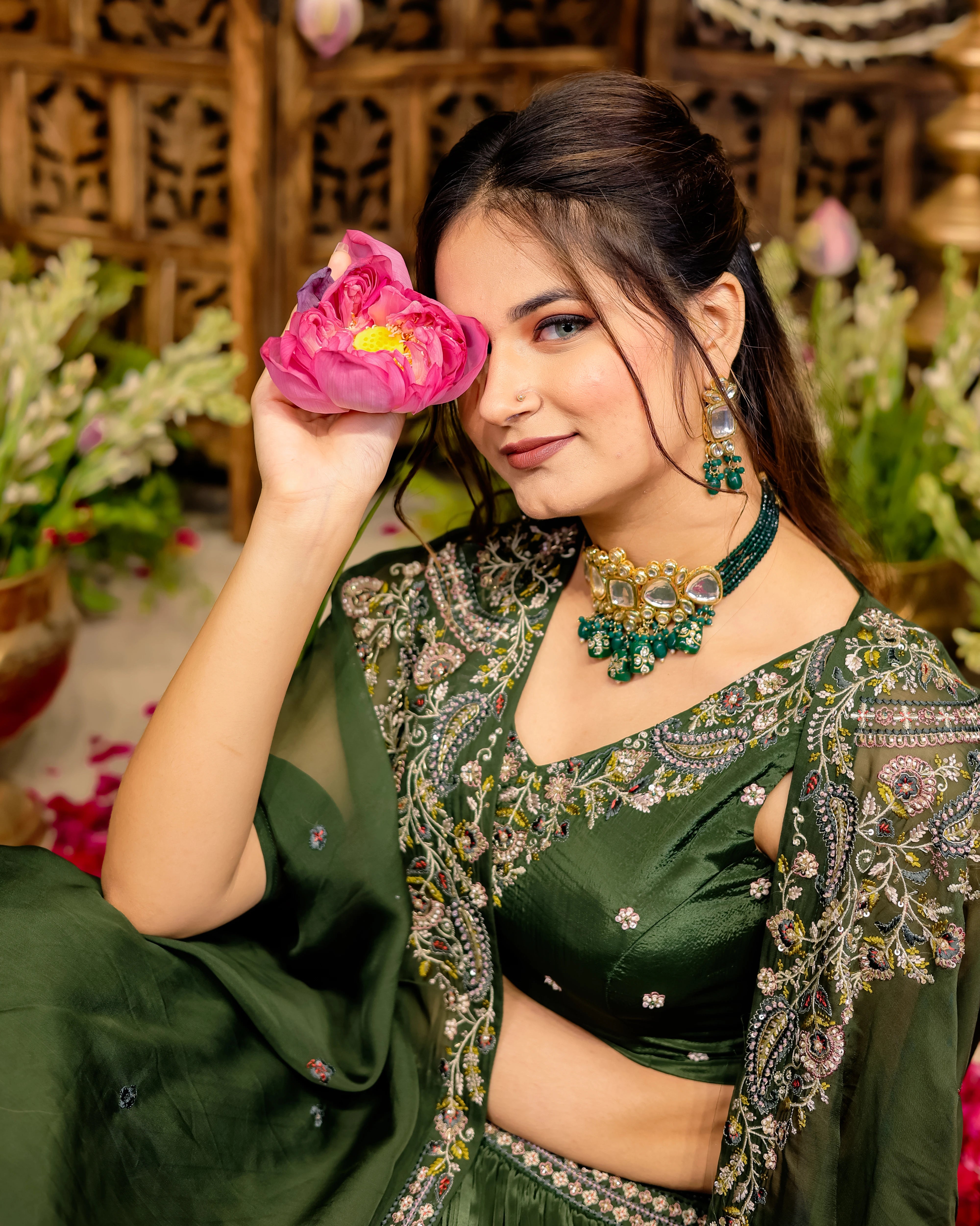 Close-up of olive green silk blouse with detailed Resham and sequin embroidery and emerald jewelry.