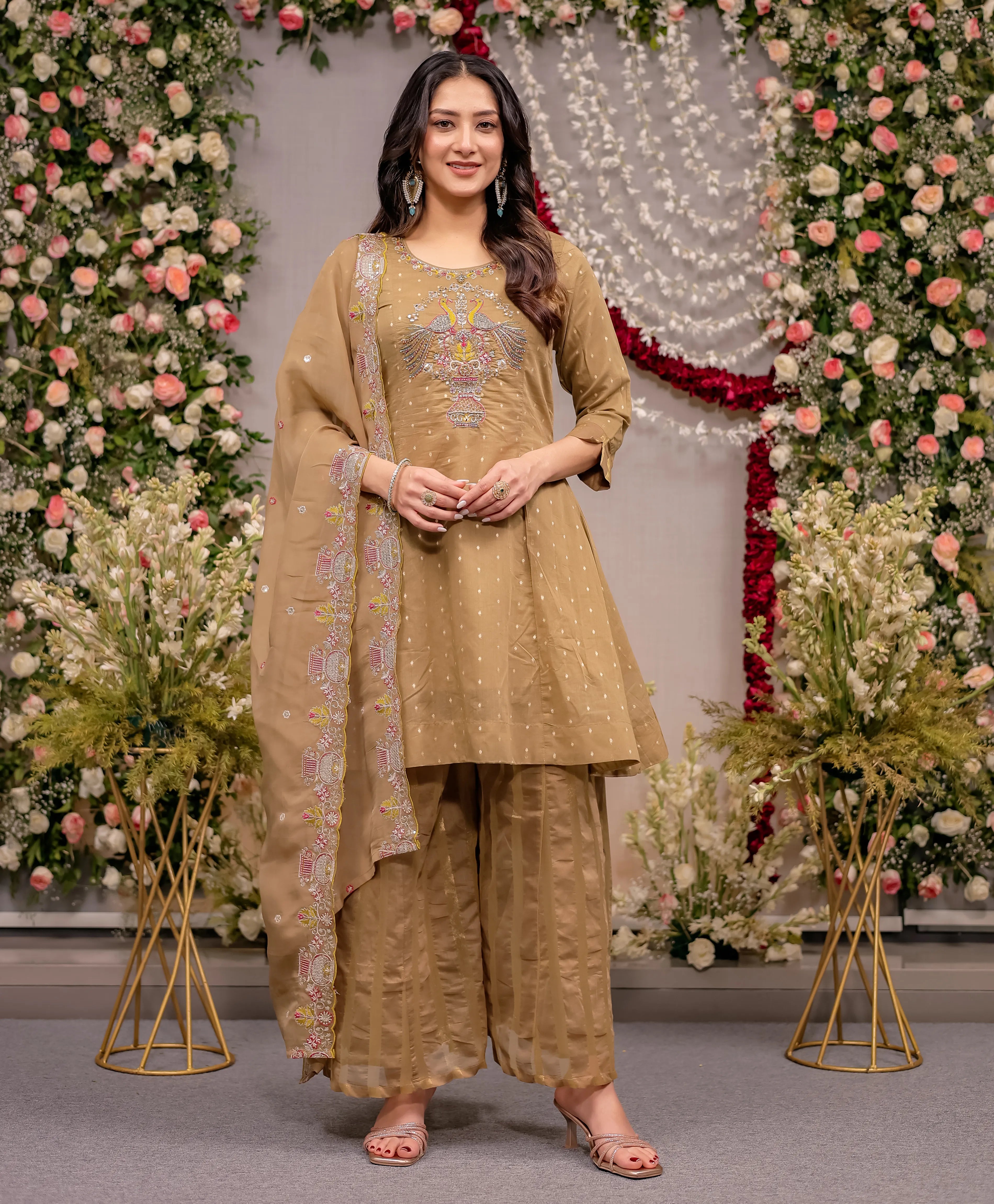 Woman in traditional beige outfit with floral decorations in the background