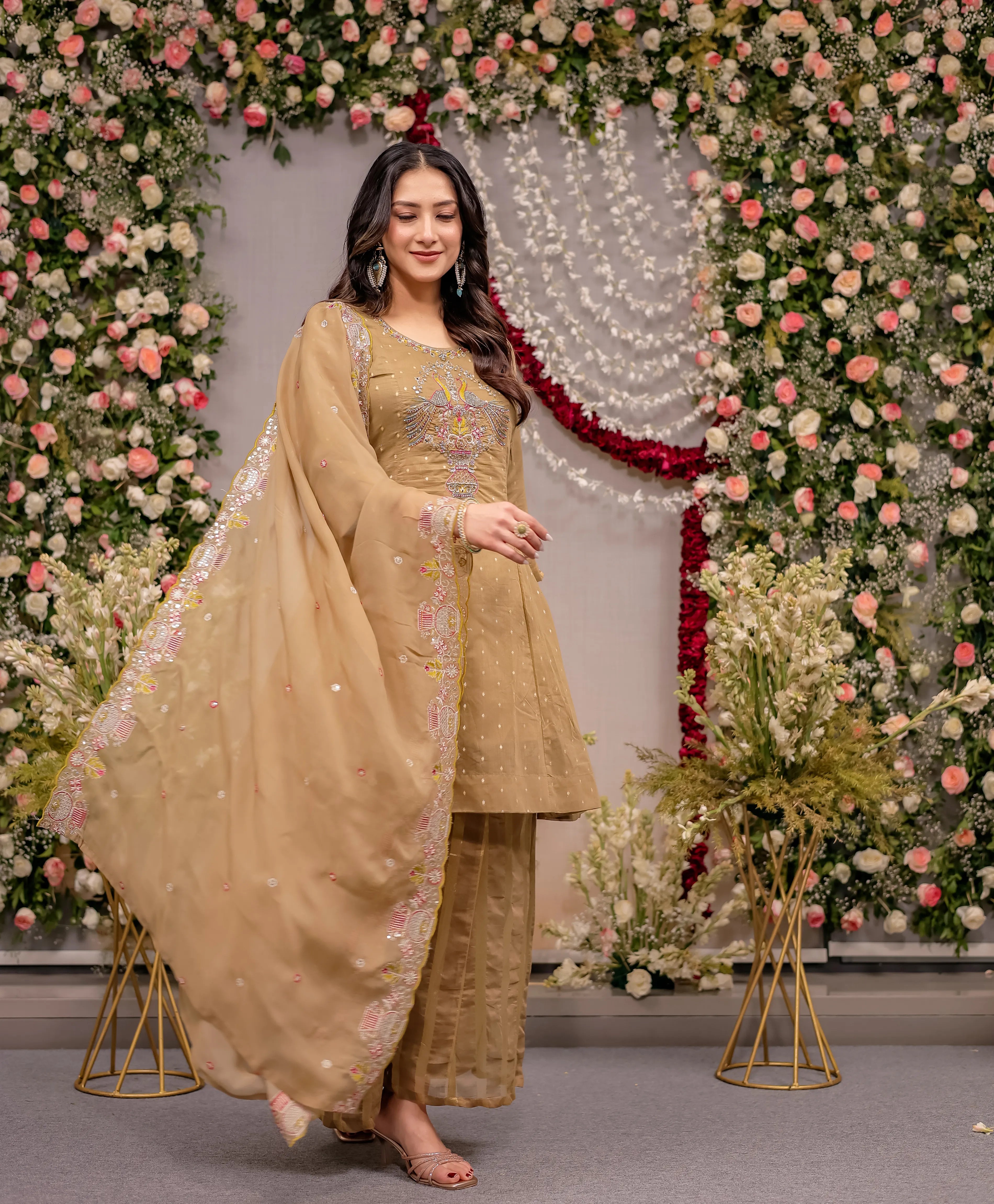 Woman in a traditional outfit standing in front of a floral decorated backdrop