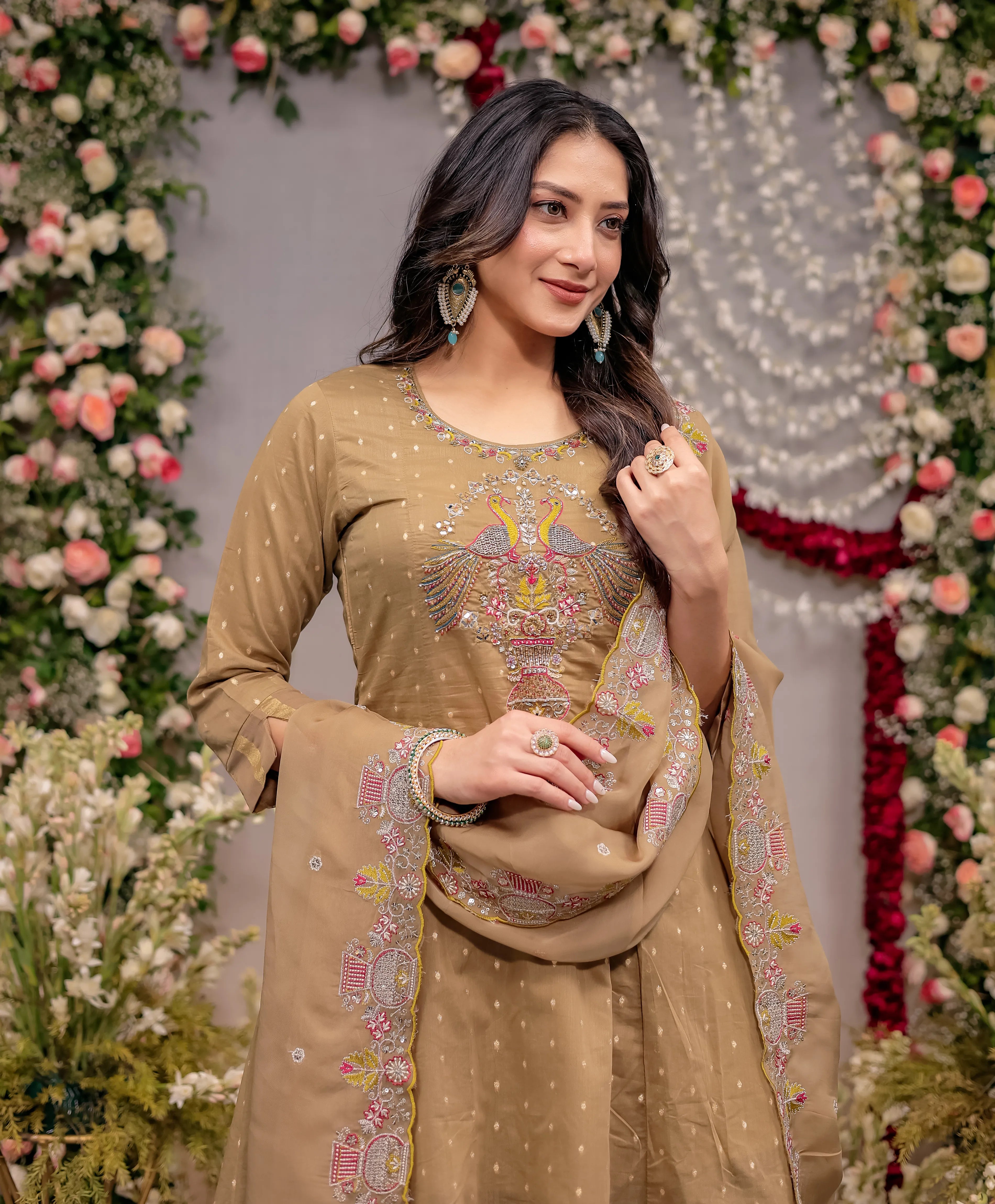 Woman in a beige embroidered traditional outfit with floral decorations in the background