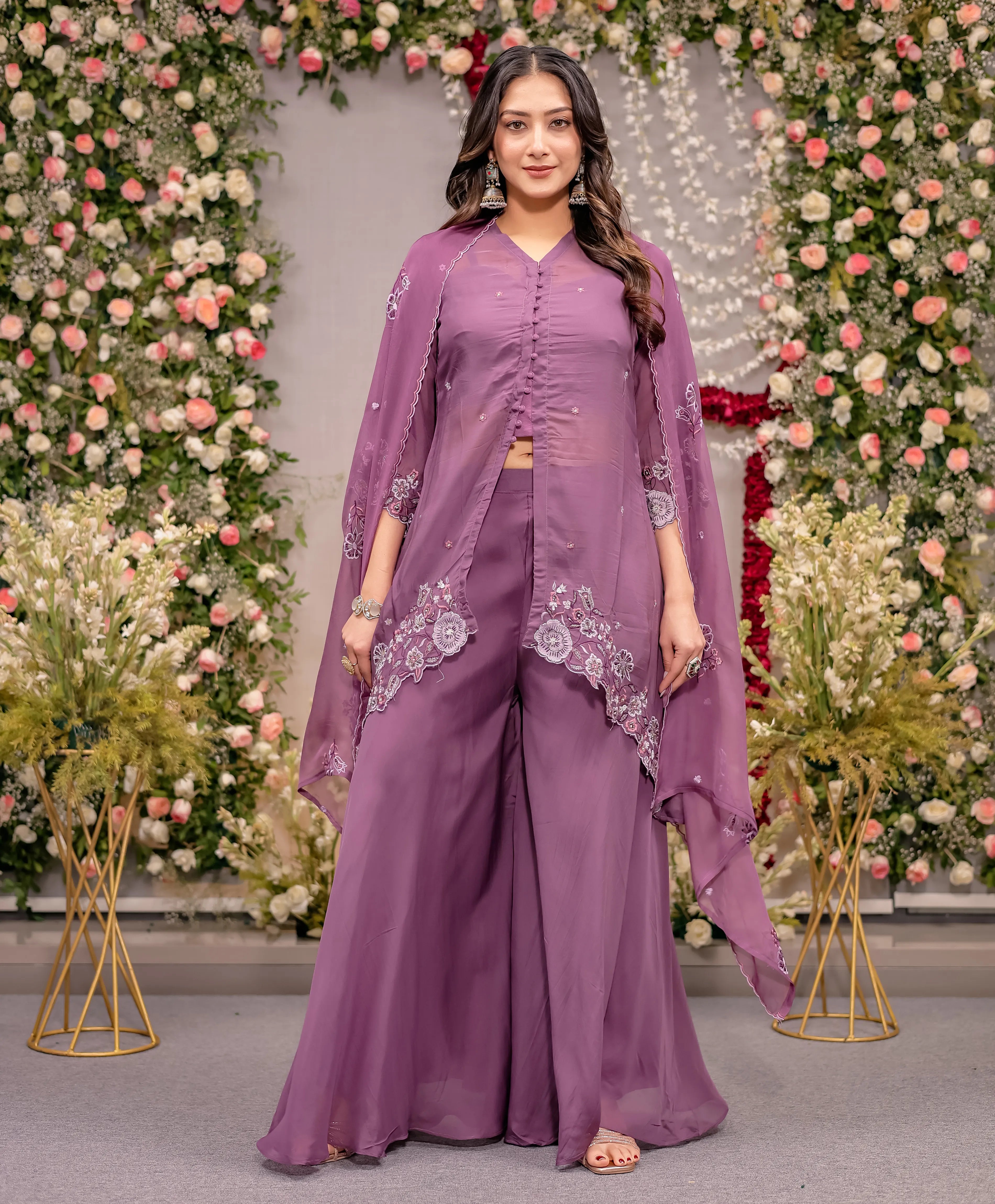 Woman in a purple traditional outfit standing in front of floral decorations