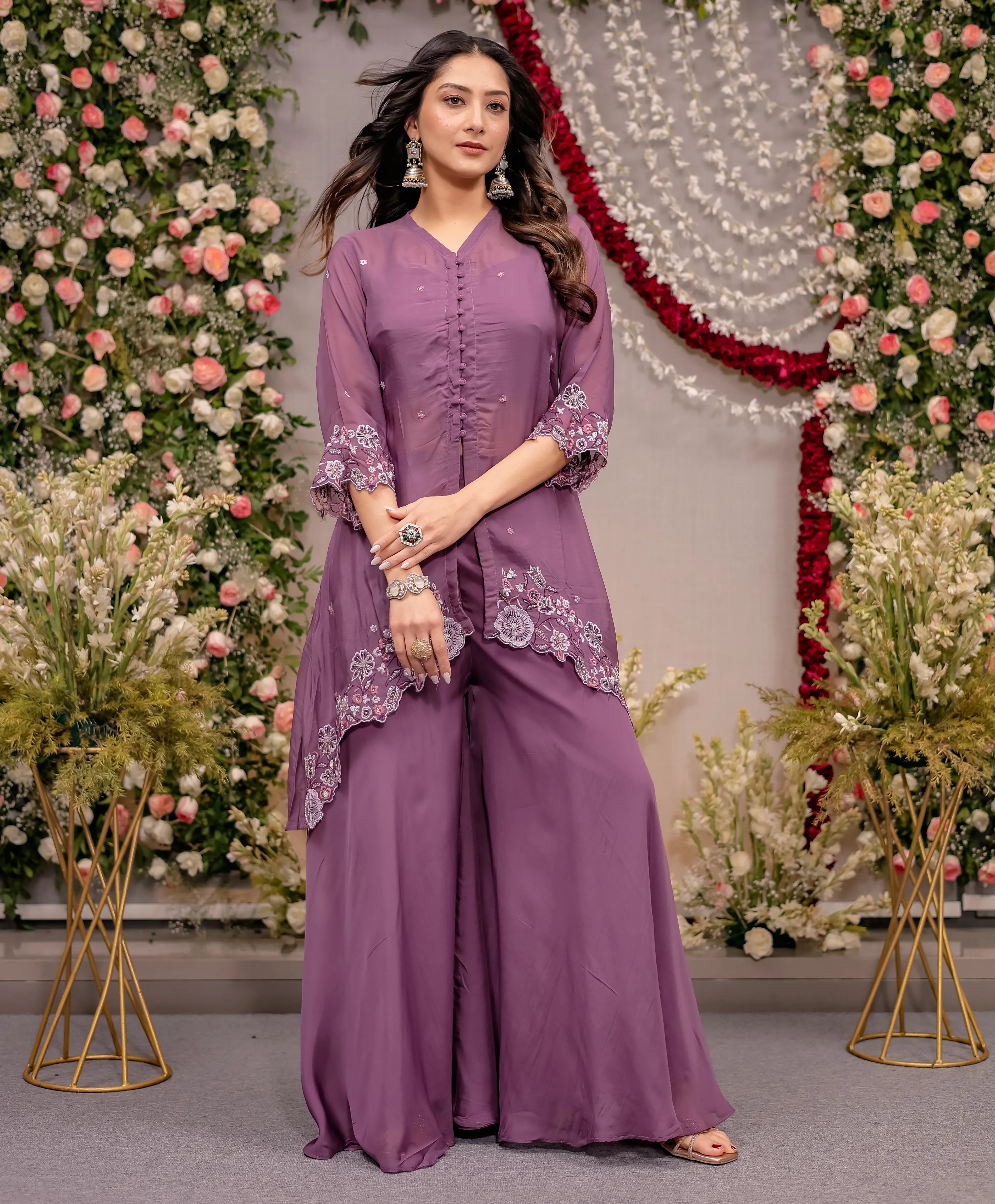 Woman in a purple traditional outfit with floral decorations and flowers in the background
