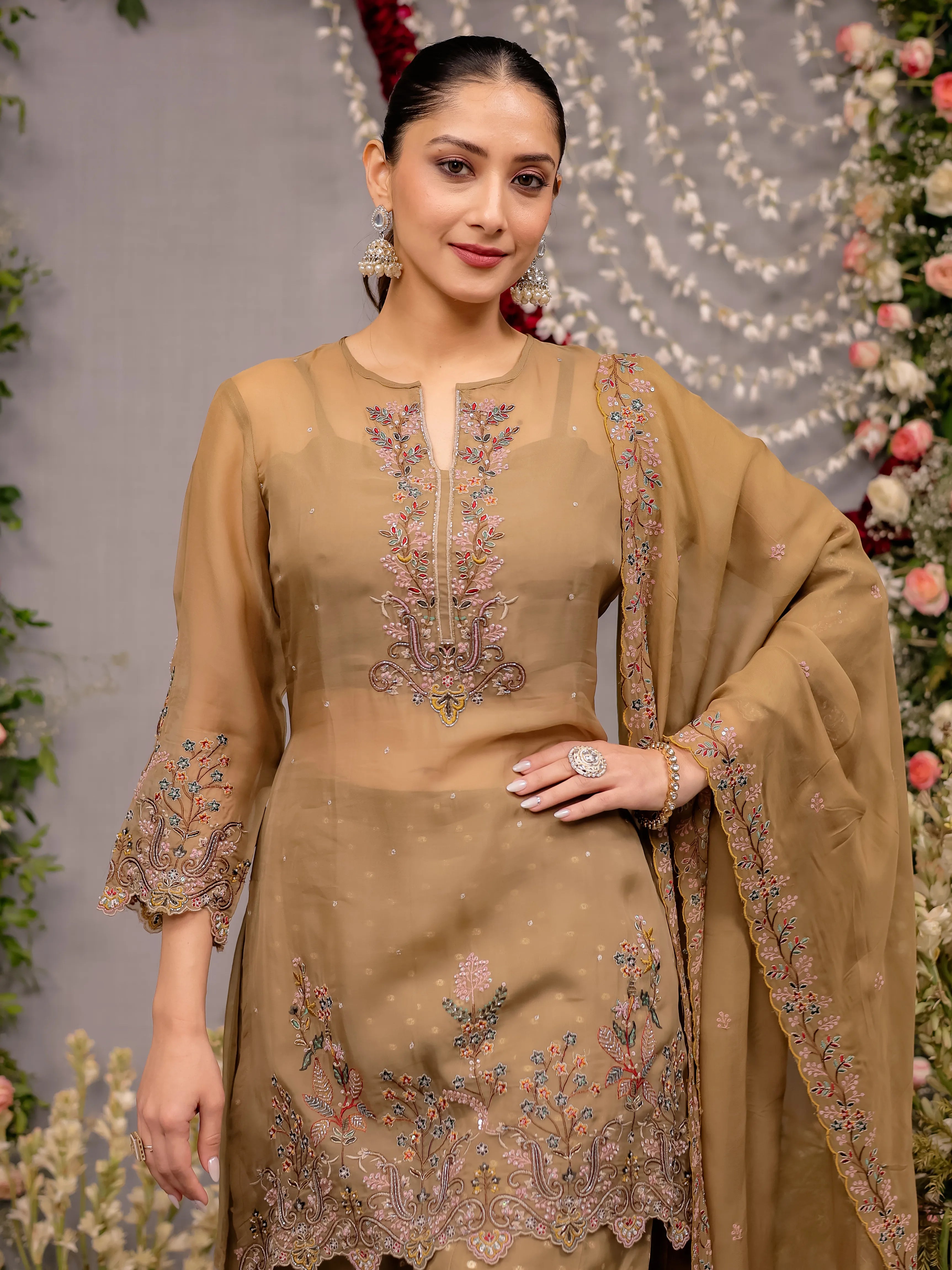 Woman wearing a beige embroidered traditional outfit with a floral background