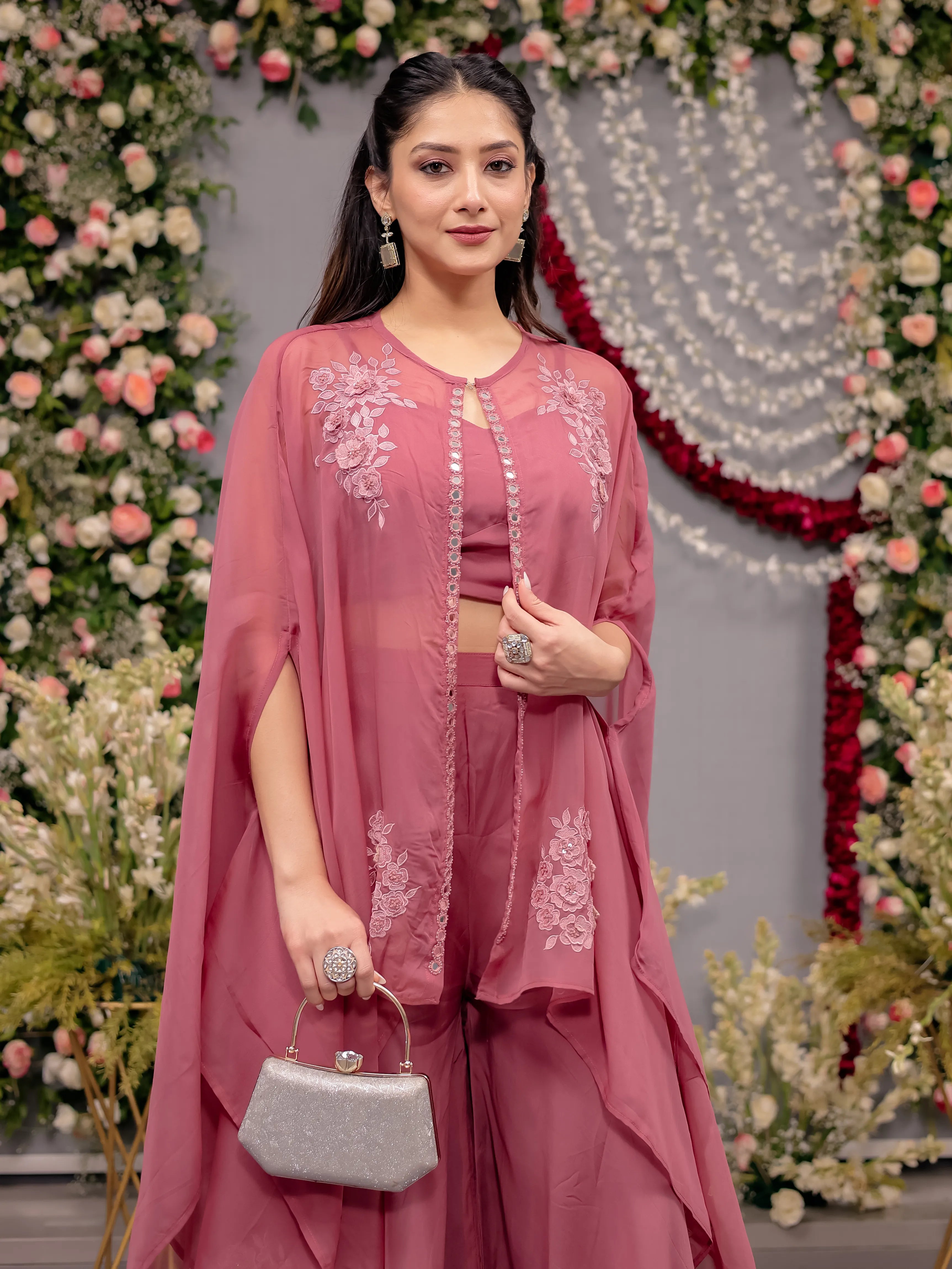Woman in a pink traditional outfit with floral decorations in the background