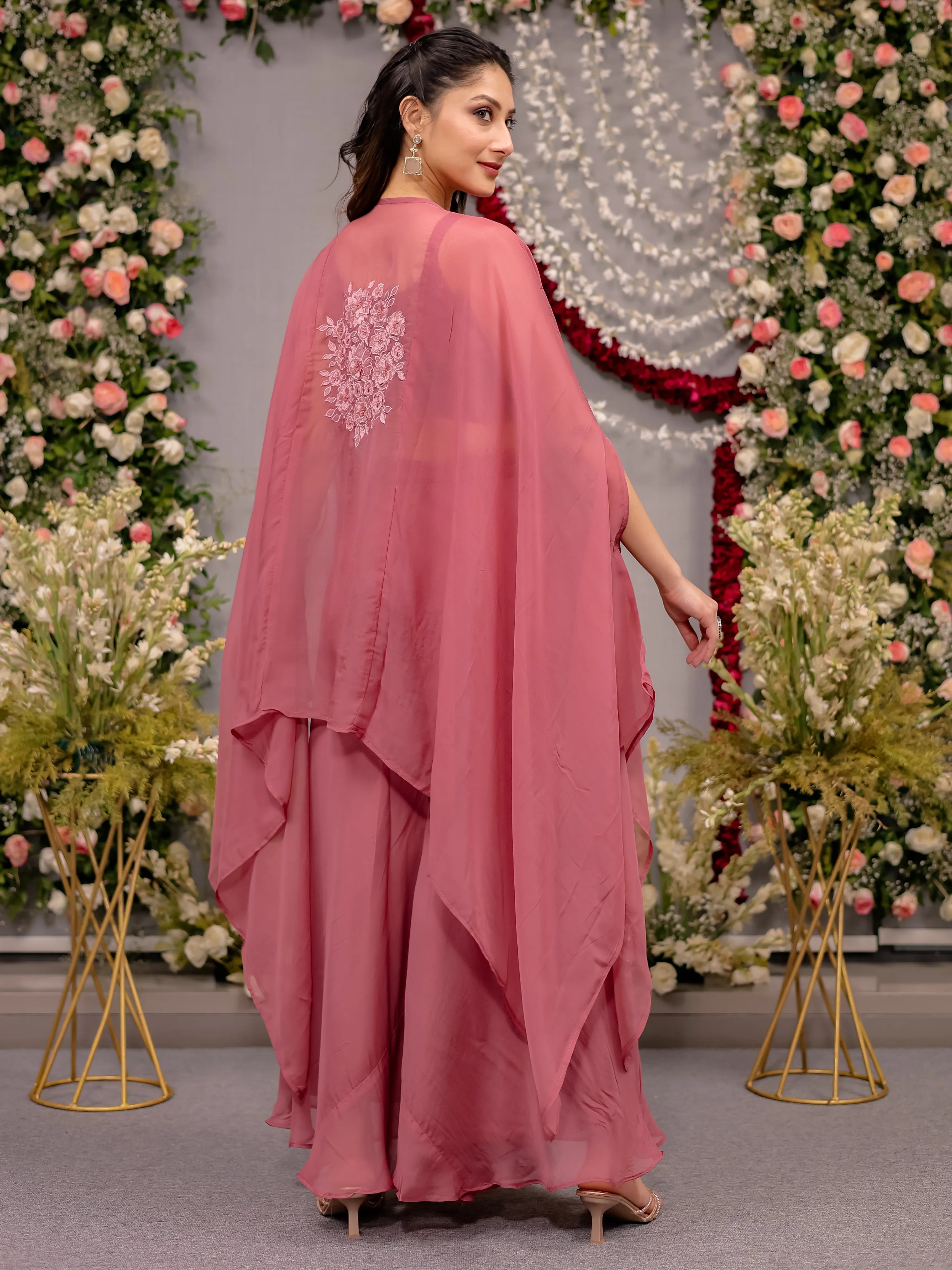 Woman in a pink dress with floral decorations in the background