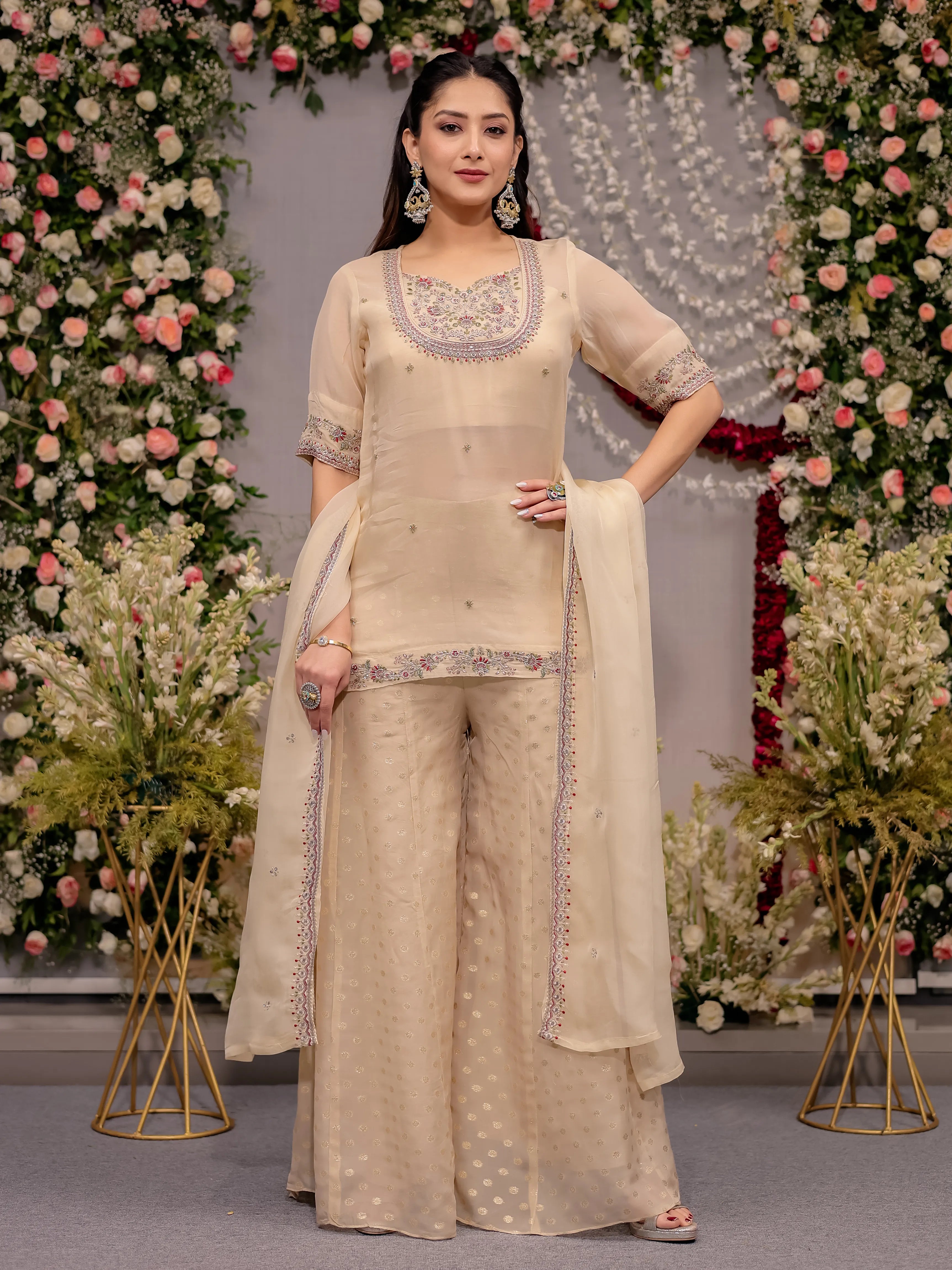 Woman in a beige traditional outfit with floral decorations in the background