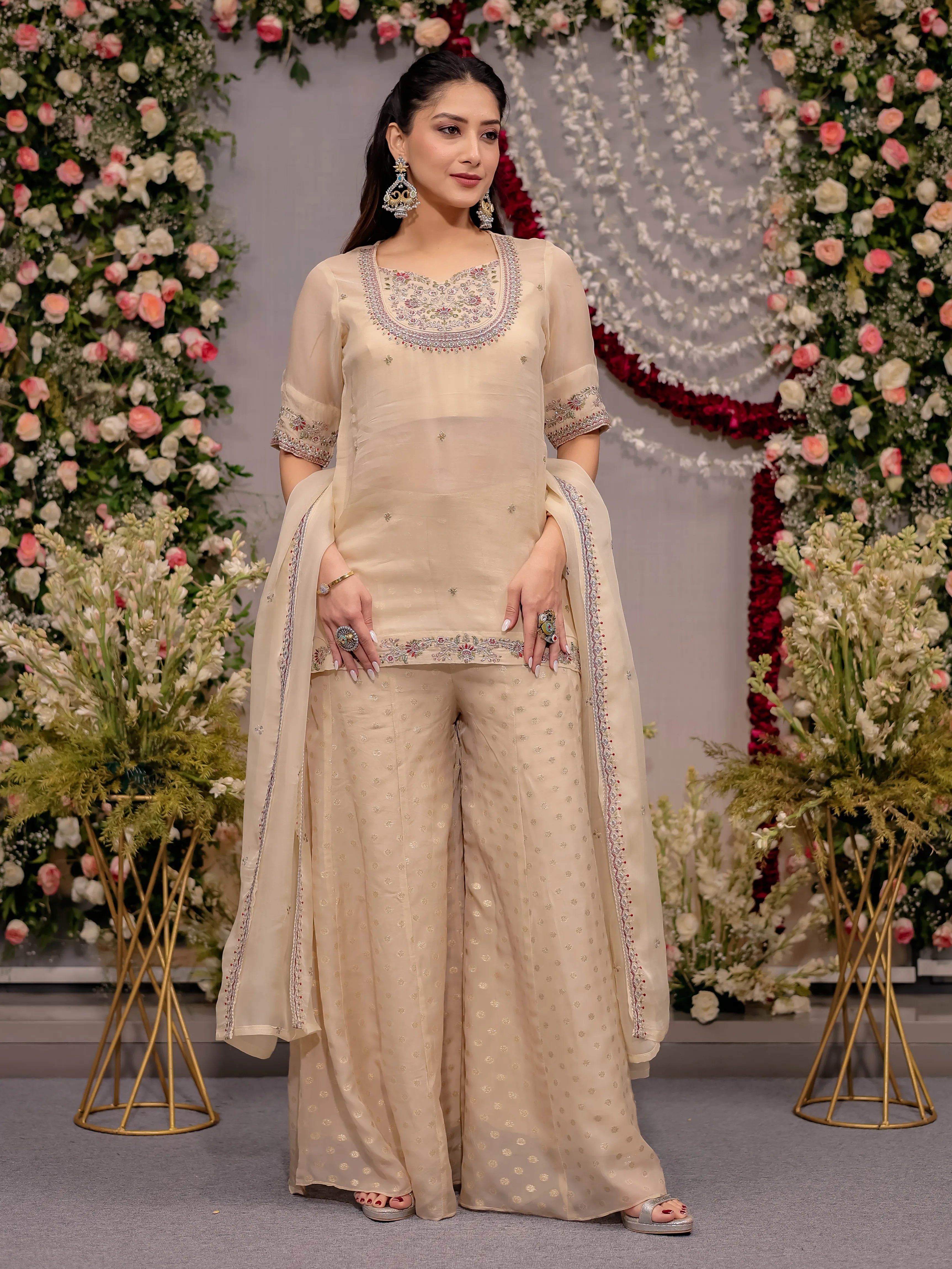 Woman in a beige traditional outfit with floral decorations in the background