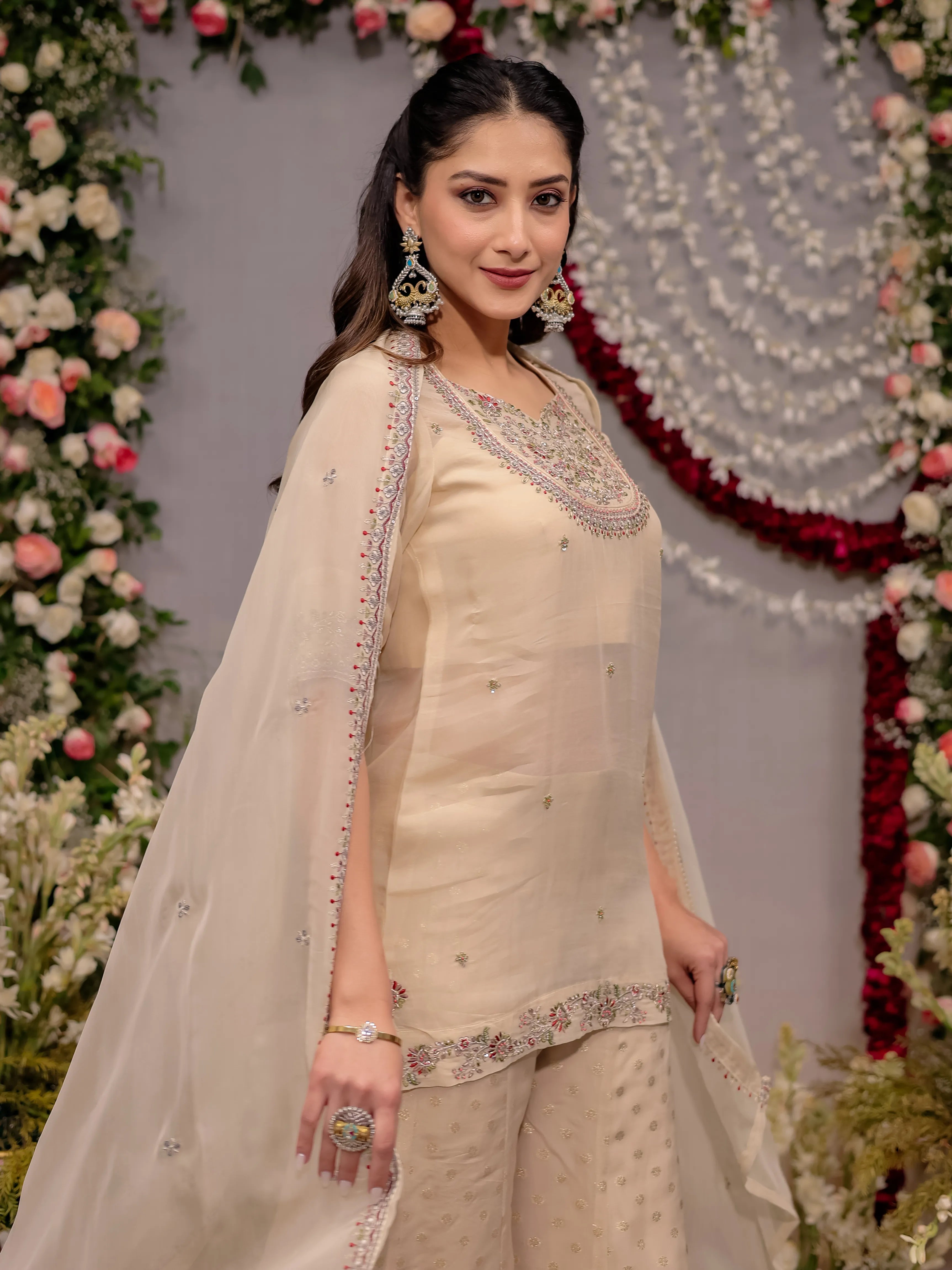 Woman in a beige traditional outfit with floral decorations in the background
