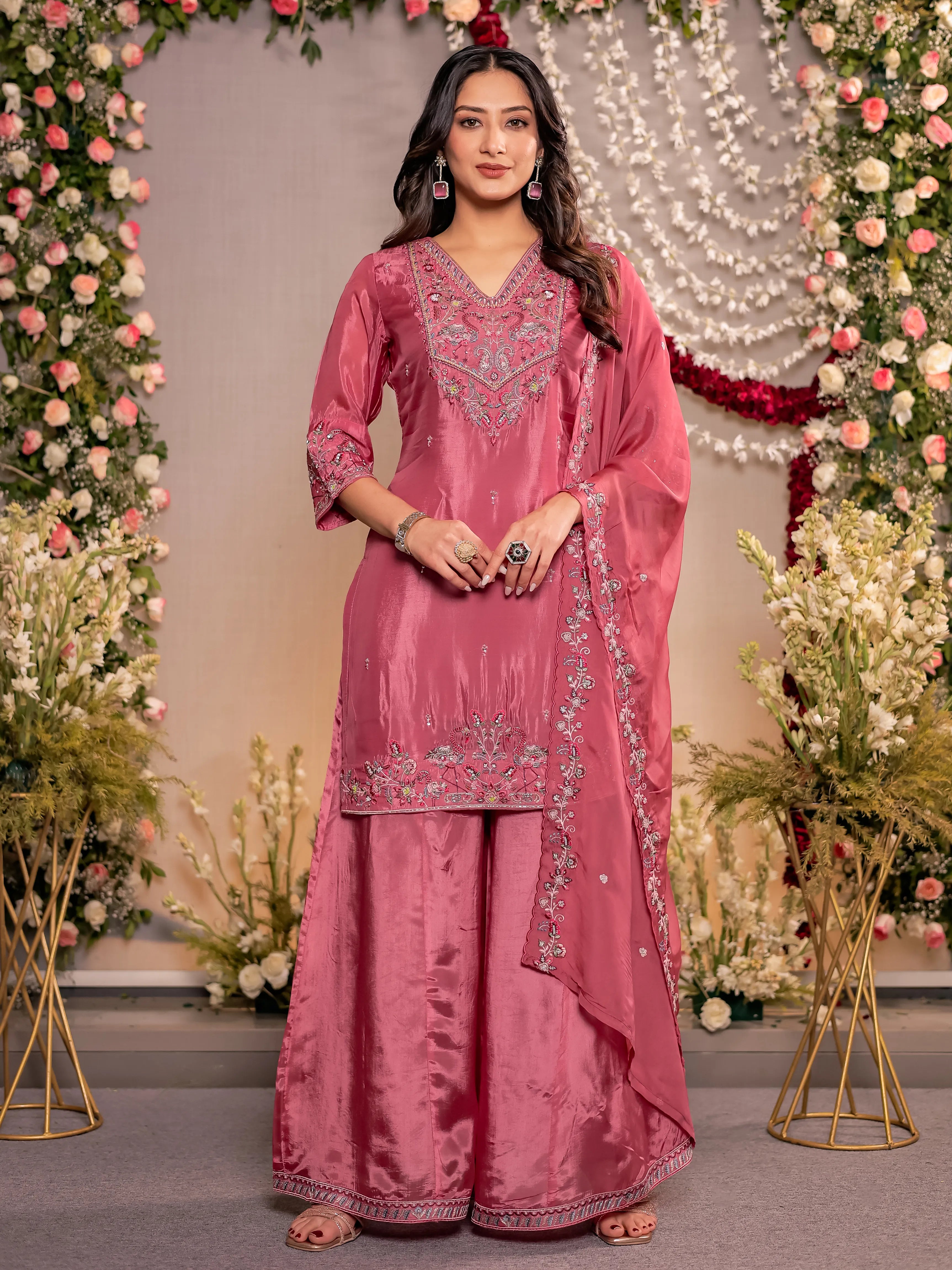 Woman in a pink traditional outfit with floral decorations in the background
