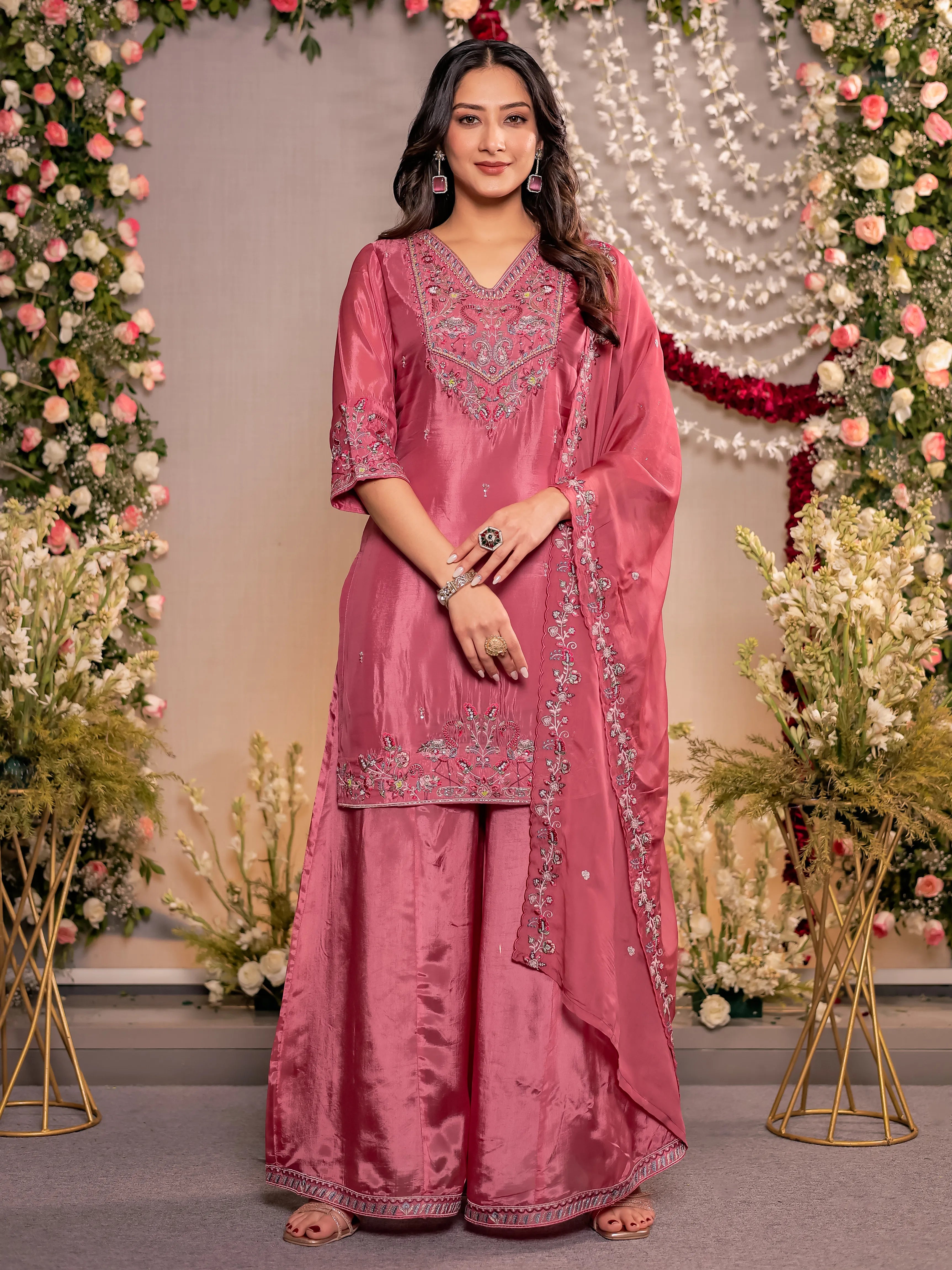 Woman in a pink traditional outfit with floral decorations in the background