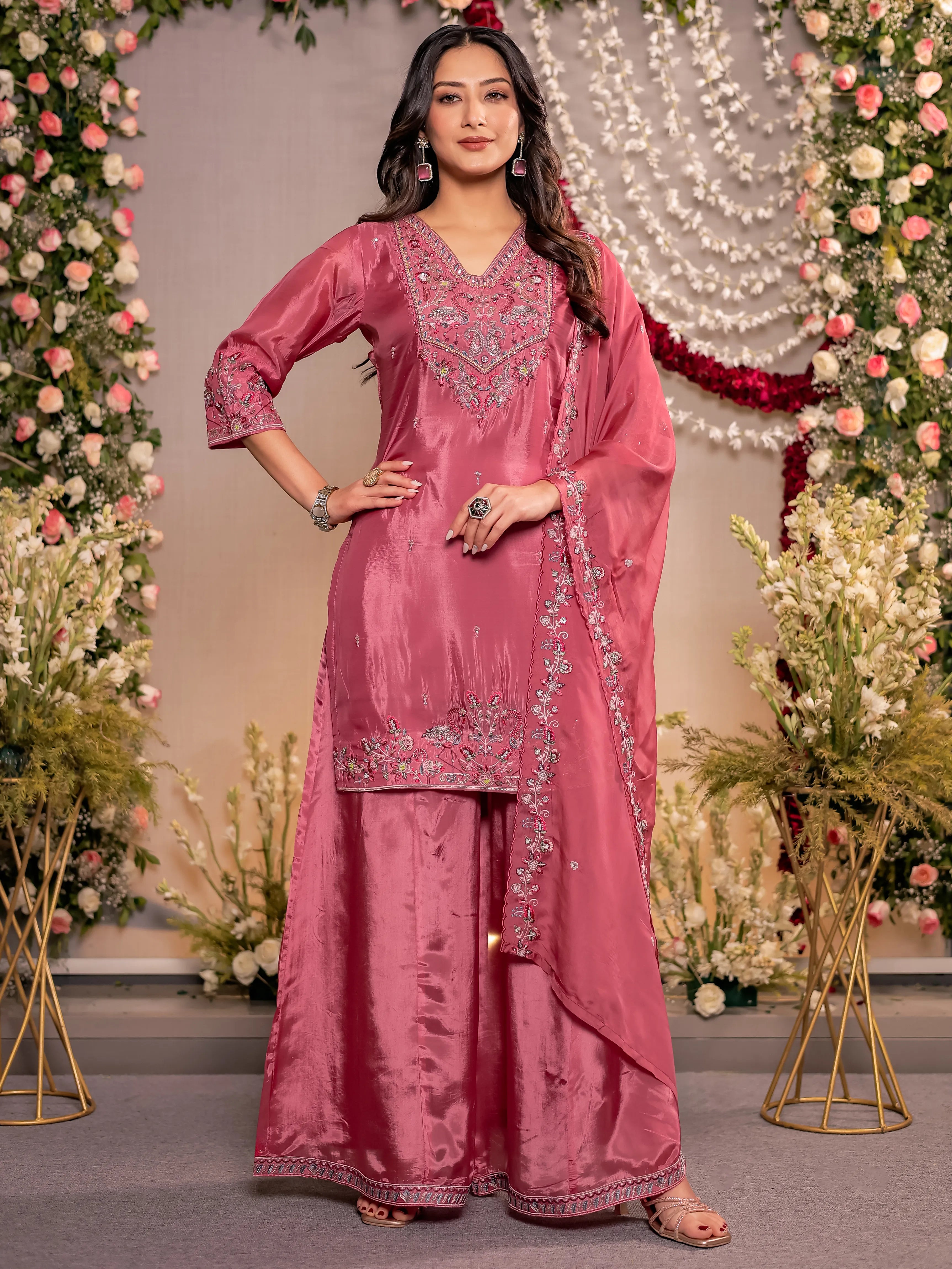 Woman in a pink traditional outfit with floral decorations in the background