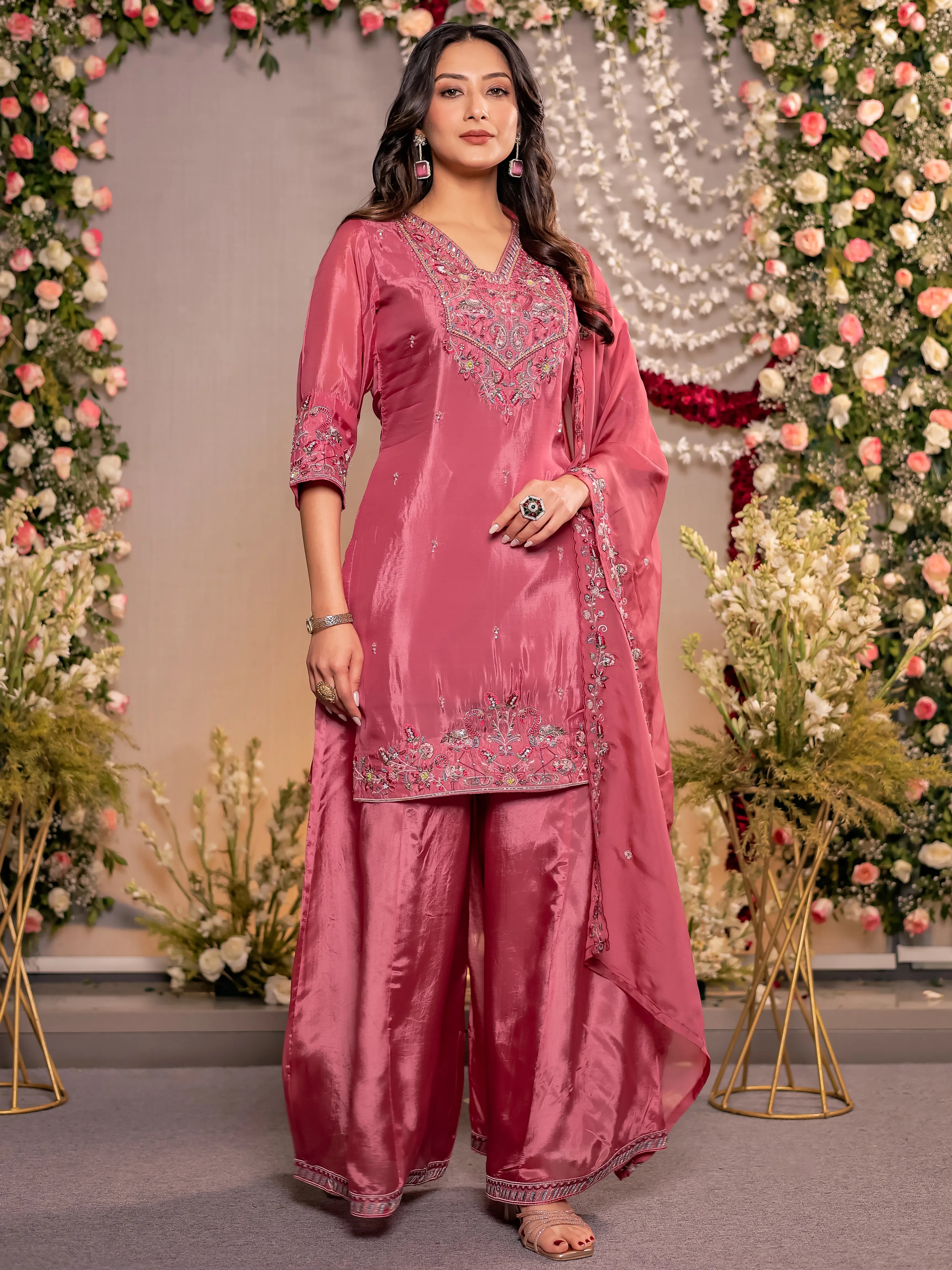 Woman in a pink traditional outfit with floral decorations in the background